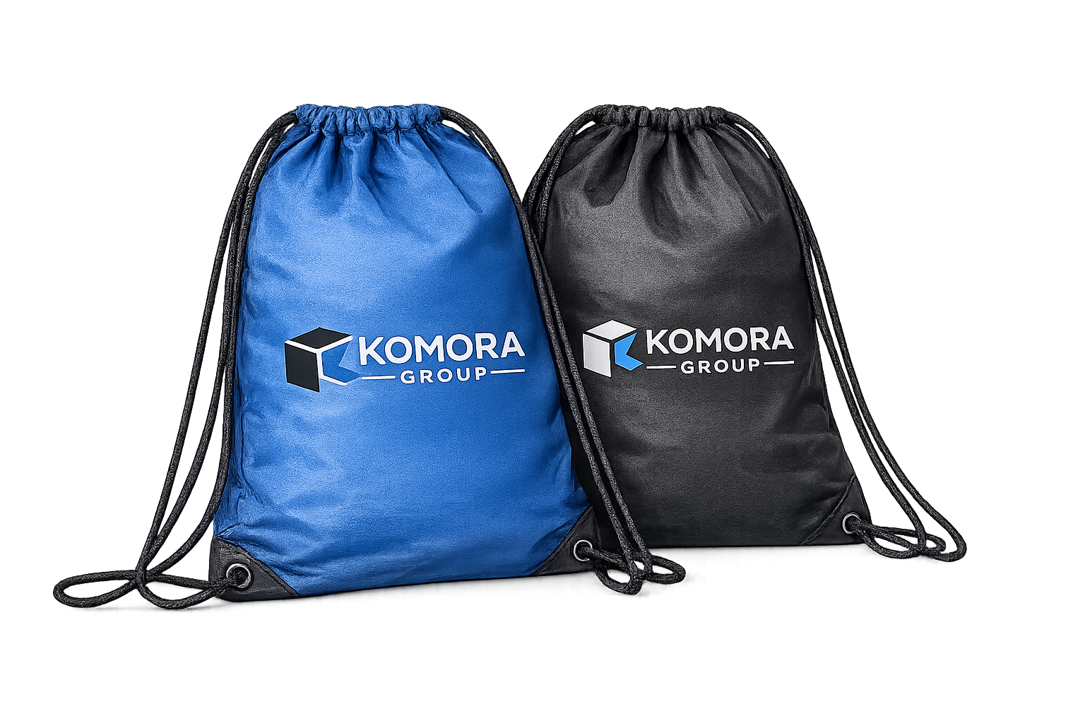 Two drawstring backpacks, one blue and one black, with the Komora Group logo printed on them. The logo includes a cube and the text 'KOMORA GROUP.'
