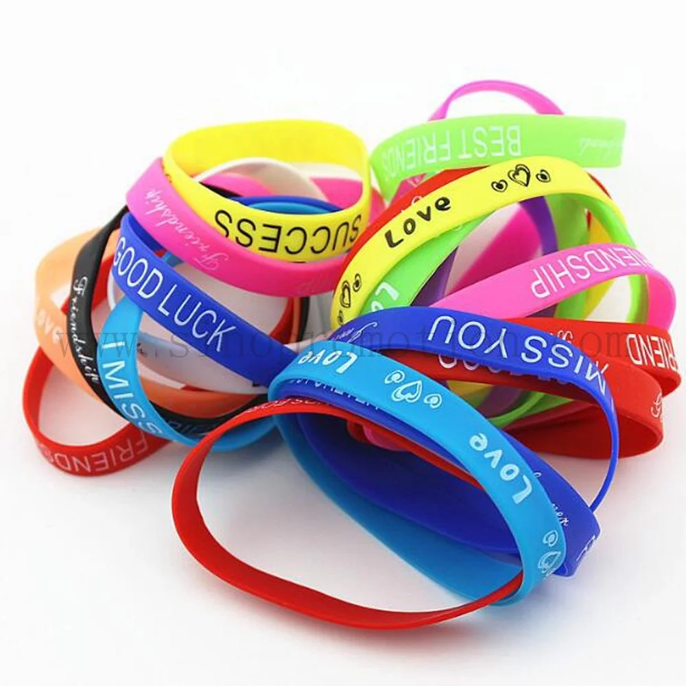 Colorful silicone wristbands with various messages and words such as "Good Luck," "Love," and "Rescue" layered and intertwined on a white background.