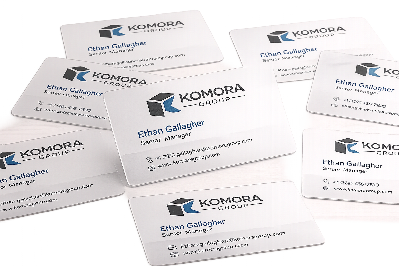 Multiple white business cards with the logo and contact information for Komora Group, displaying the name Ethan Gallagher, Senior Manager.