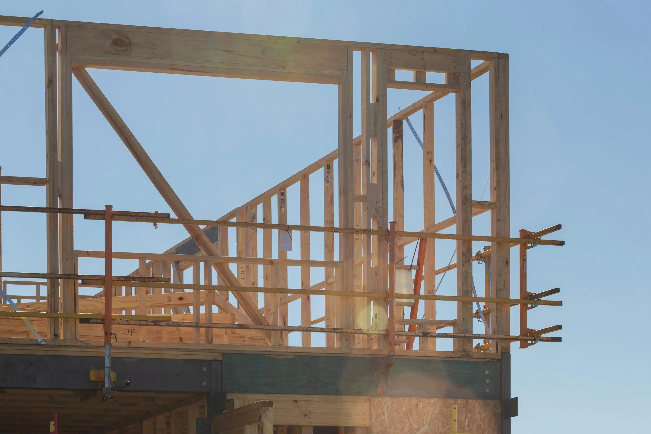 Wooden framing of a building under construction against a clear blue sky.