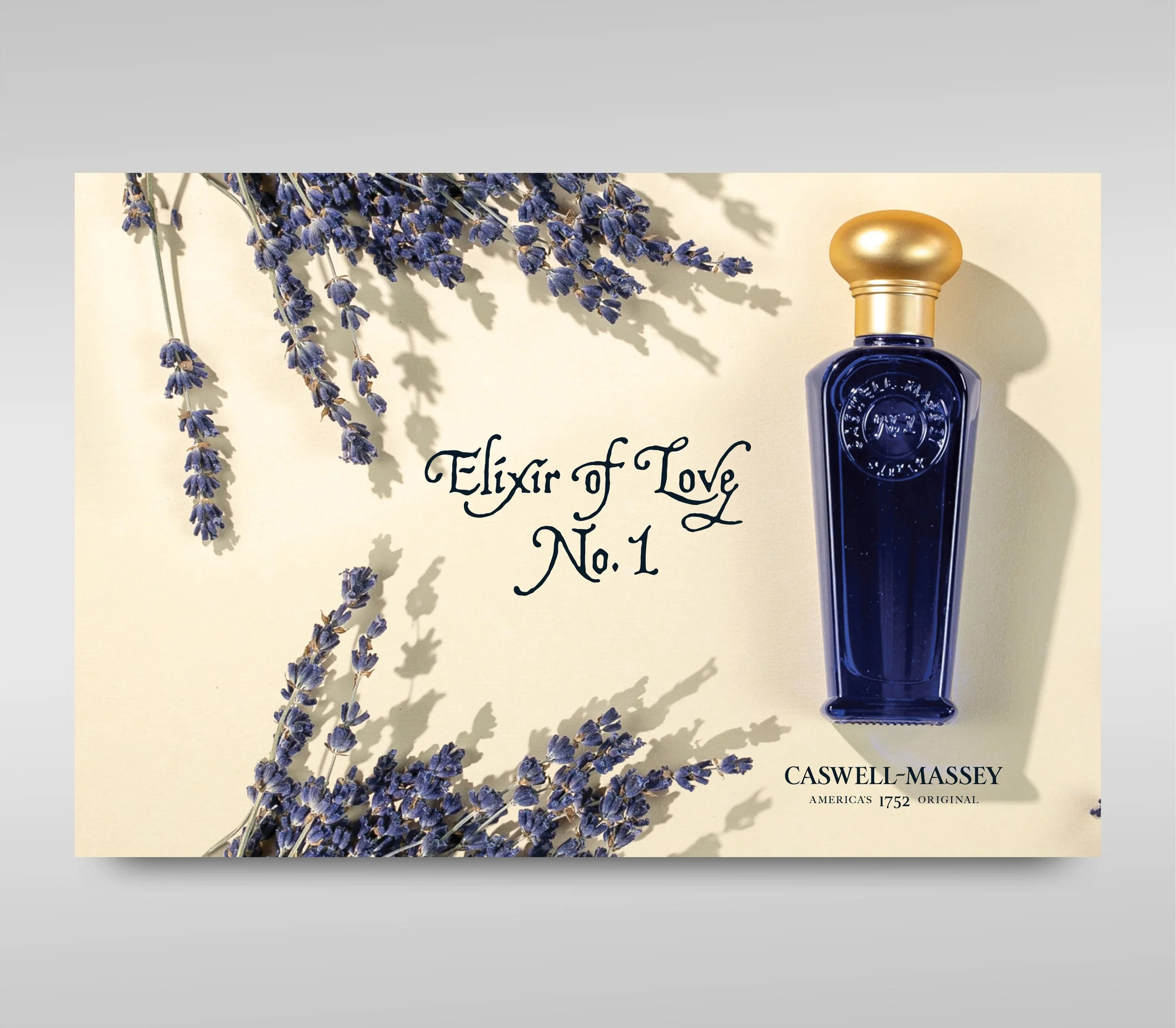 A bottle of Caswell-Massey Elixir of Love No. 1 perfume with lavender sprigs on a light background.