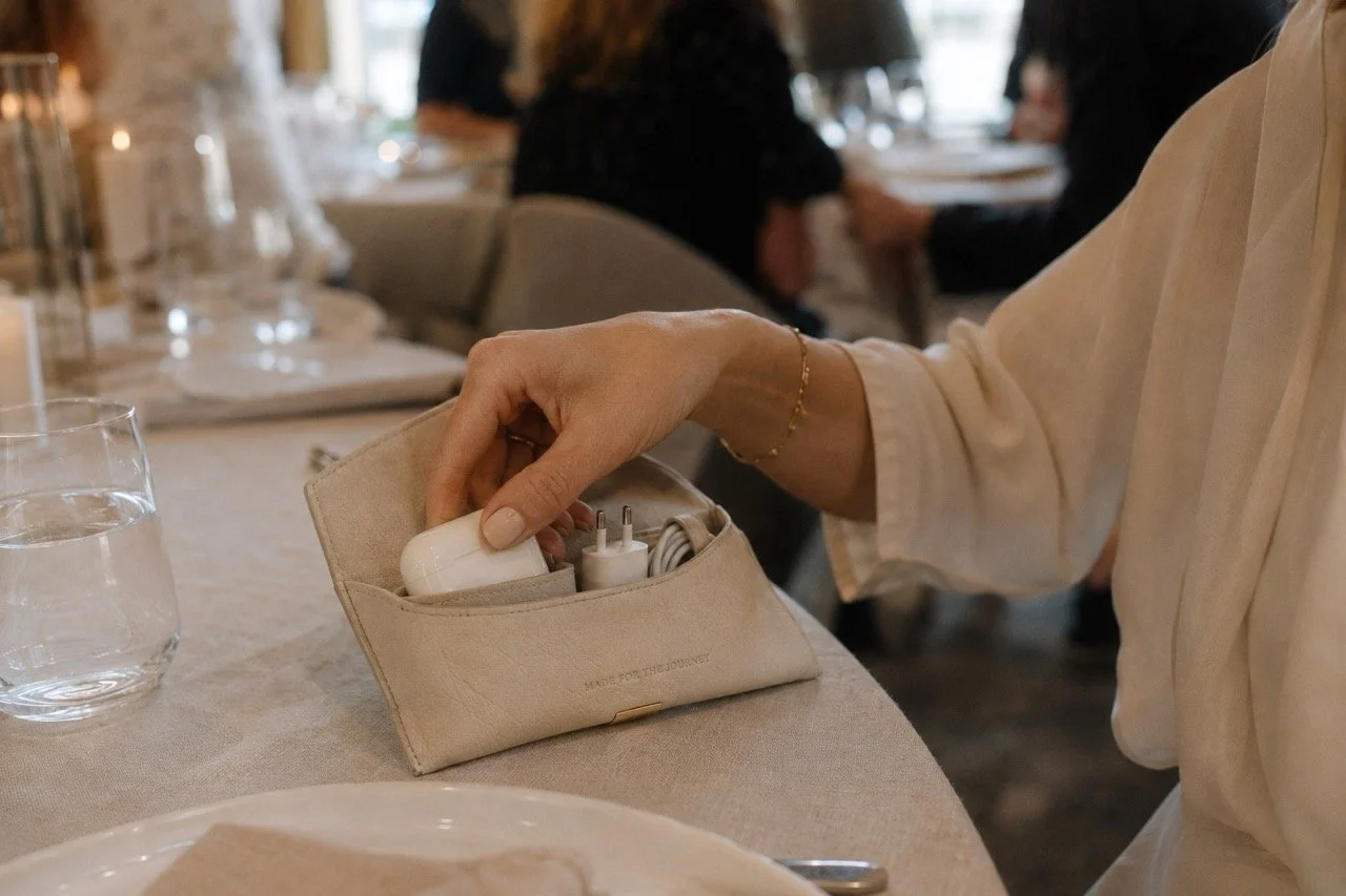 Woman placing charging accessories into a beige leather tech organizer created by Island Whisper Atelier for Irregular Lines singapore event gifting