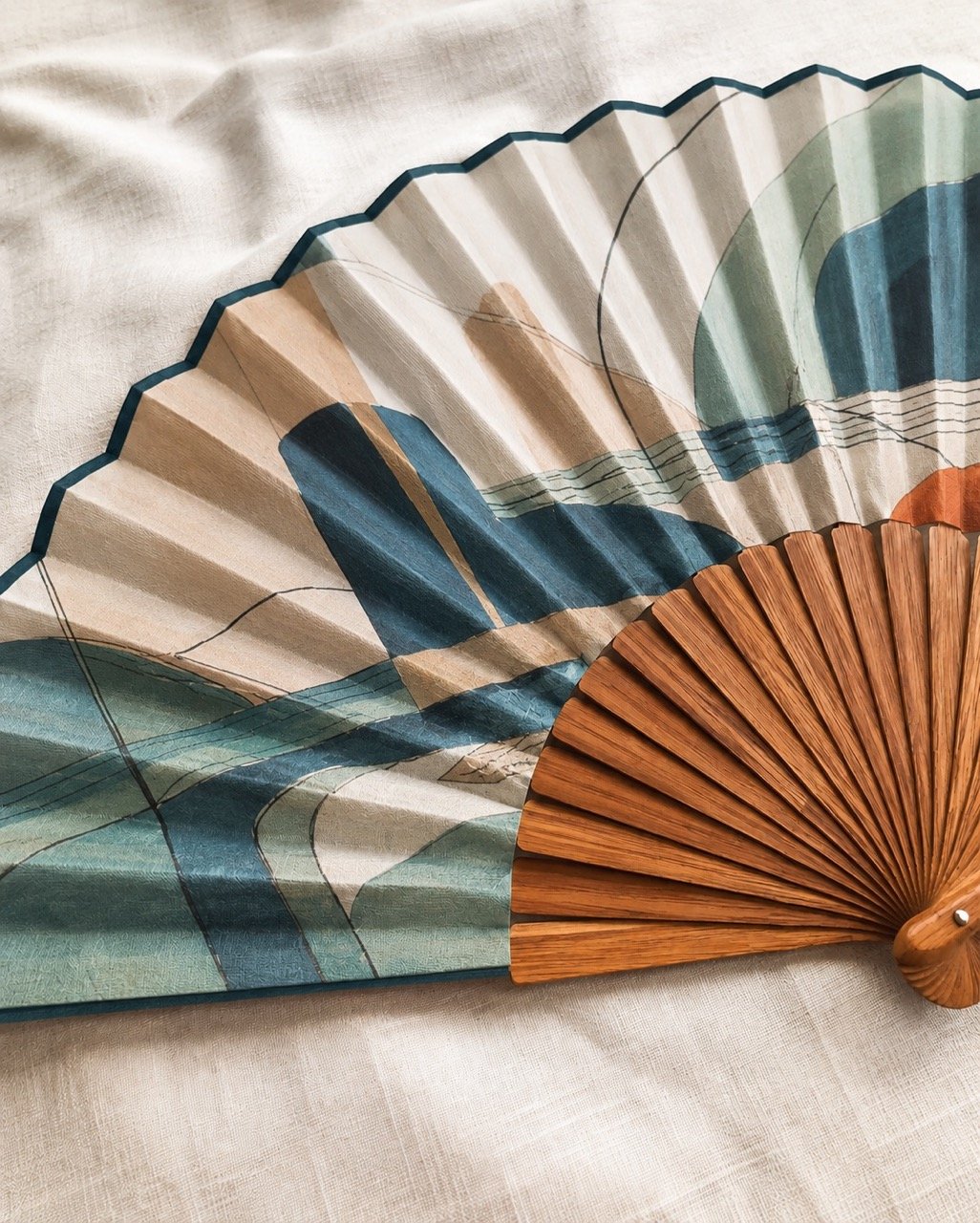 Abstract bespoke luxury hand fan in petrol blue, jade and sand with natural wood ribs by Island Whisper Atelier