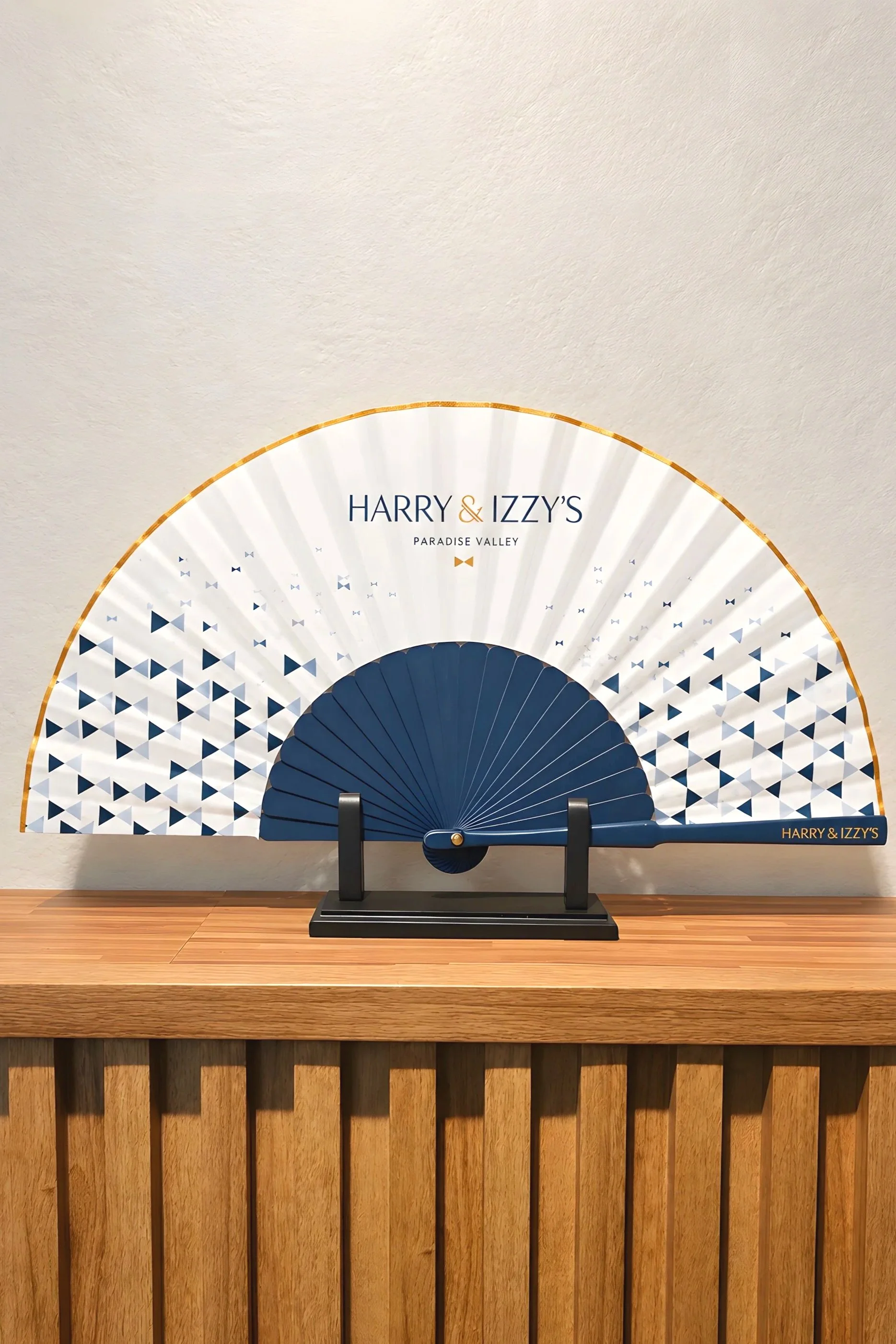 Artisanal detail of a luxury hand fan featuring a hand-painted acrylic edge. A subtle finish that transforms the piece and reinforces its unique character, especially for bespoke hotel, brand and event projects.