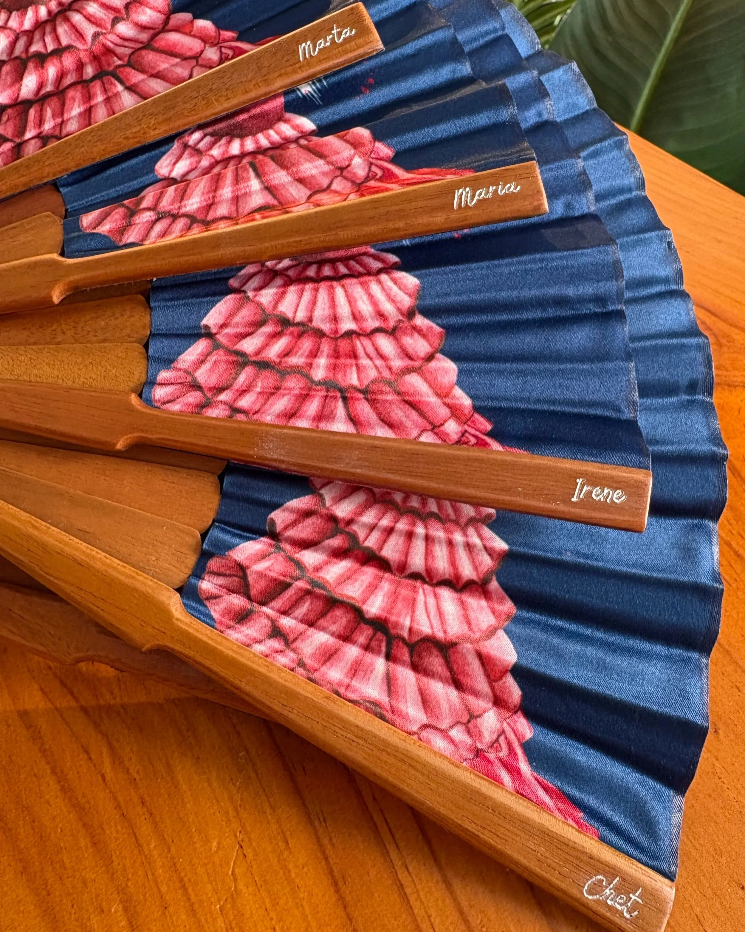 Abanicos de lujo personalizados con nombres individuales grabados sobre varillas de madera natural.