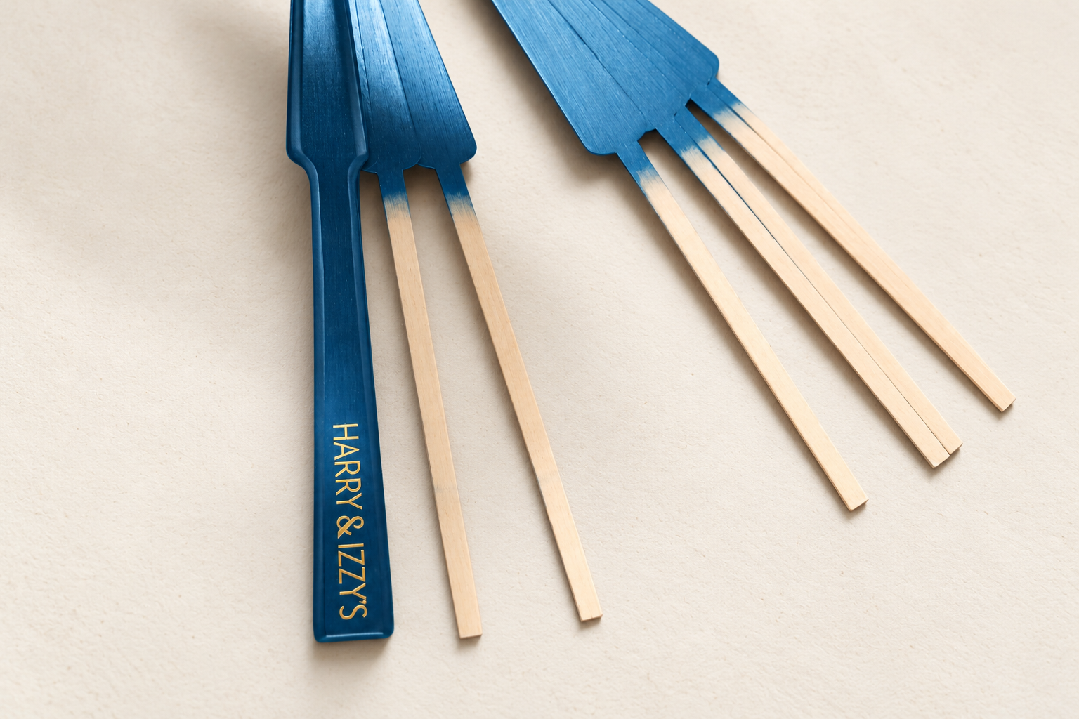 Detail of a bespoke luxury hand fan featuring deep blue wooden sticks and gold personalization. Colours, finishes and decorative details can be tailored to the visual identity of each hotel, resort, brand or event.