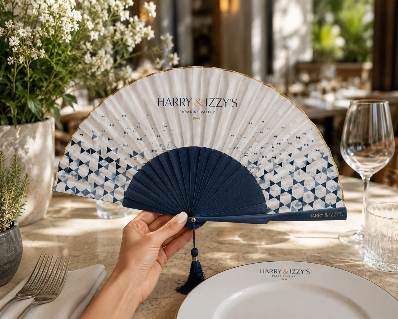 Bespoke luxury hand fan for Harry & Izzy’s restaurant, featuring blue painted wooden ribs, gold engraving and custom artwork by Island Whisper Atelier.