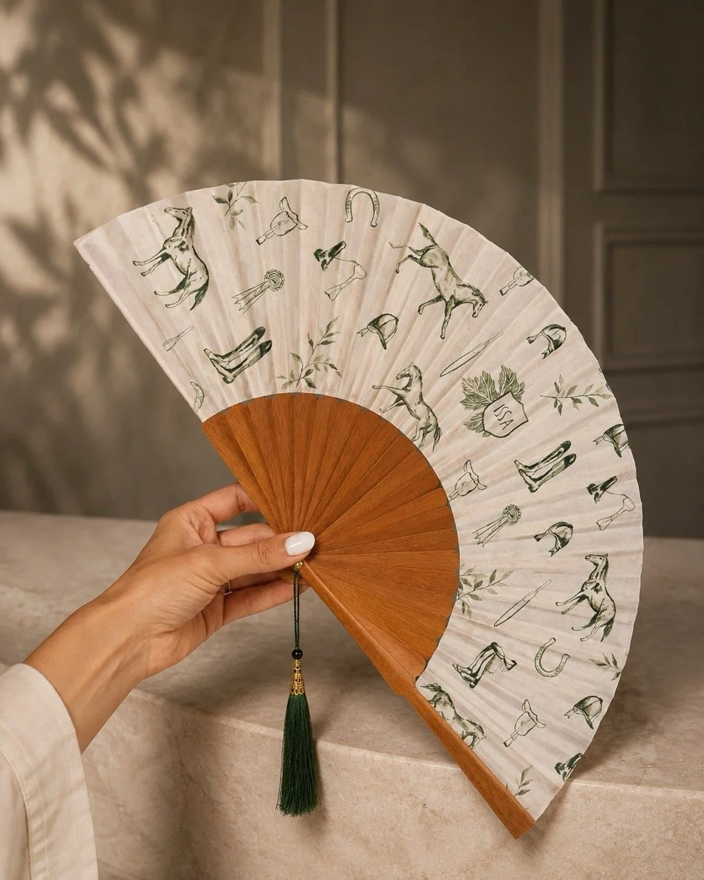 Bespoke equestrian hand fan with natural wooden ribs, original horse illustrations and tassel, created for a luxury hospitality concept in Rumania.