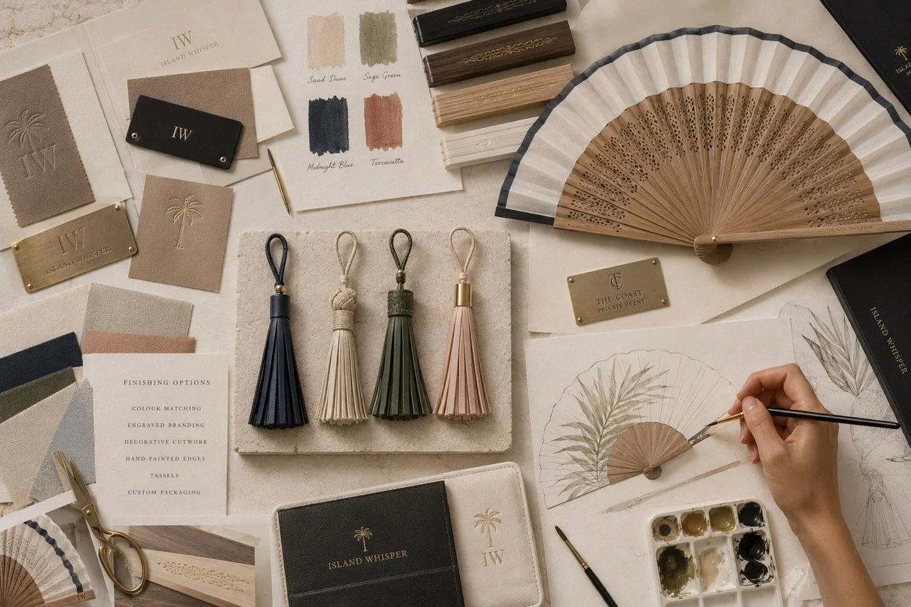 Bespoke luxury hand fan customisation by Island Whisper Atelier, featuring handcrafted tassels, engraved branding, colour matching, decorative cutwork and hand-painted design details.