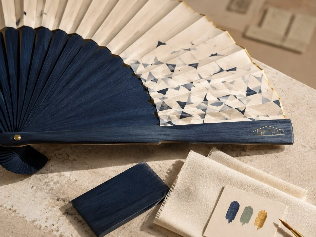 Detail of navy-dyed natural wood, gold engraving and original artwork on a bespoke luxury hand fan by Island Whisper Atelier