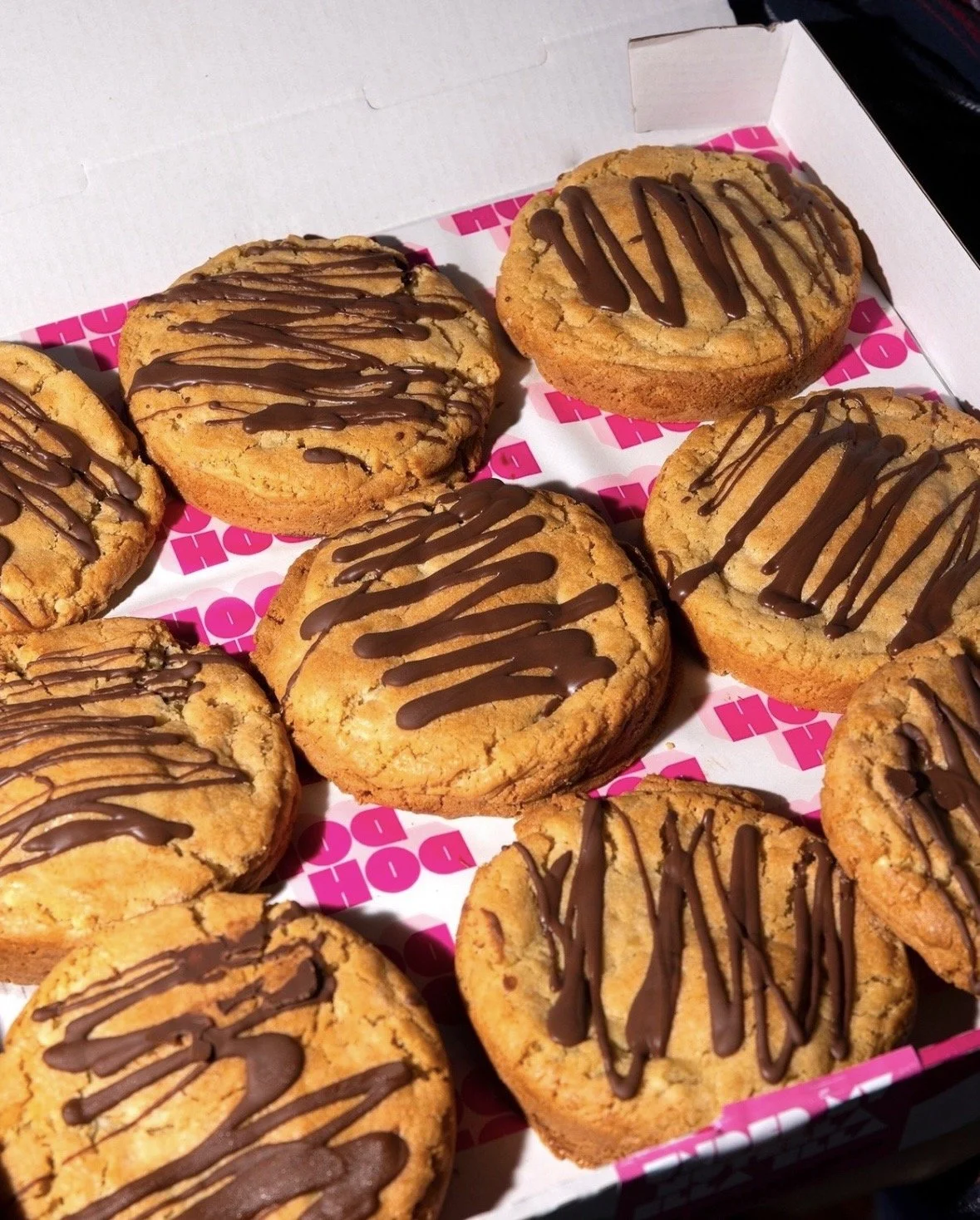 A box of assorted cookies with chocolate drizzle on top.