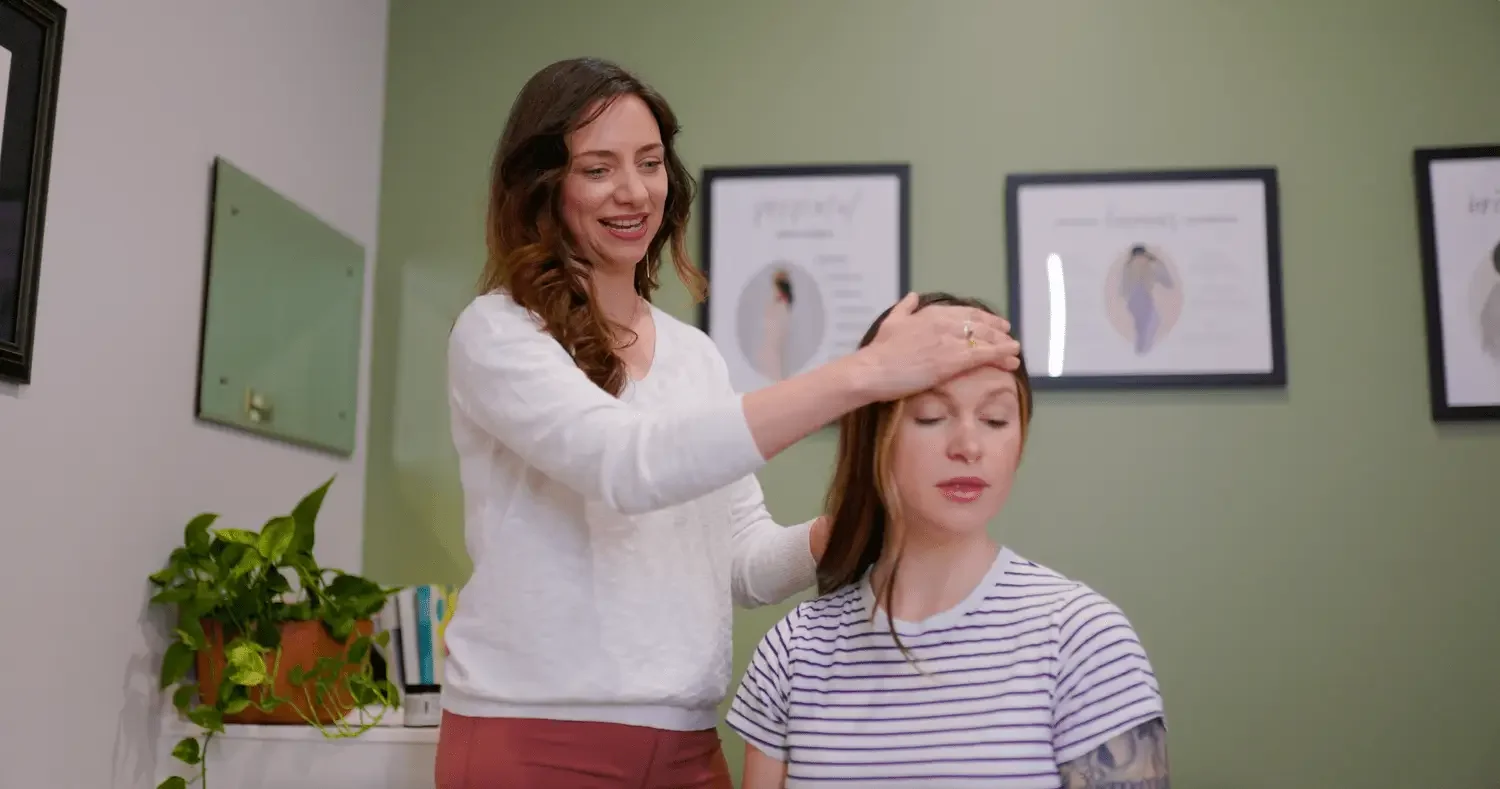 Therapist performing head massage on a woman in a clinic setting.