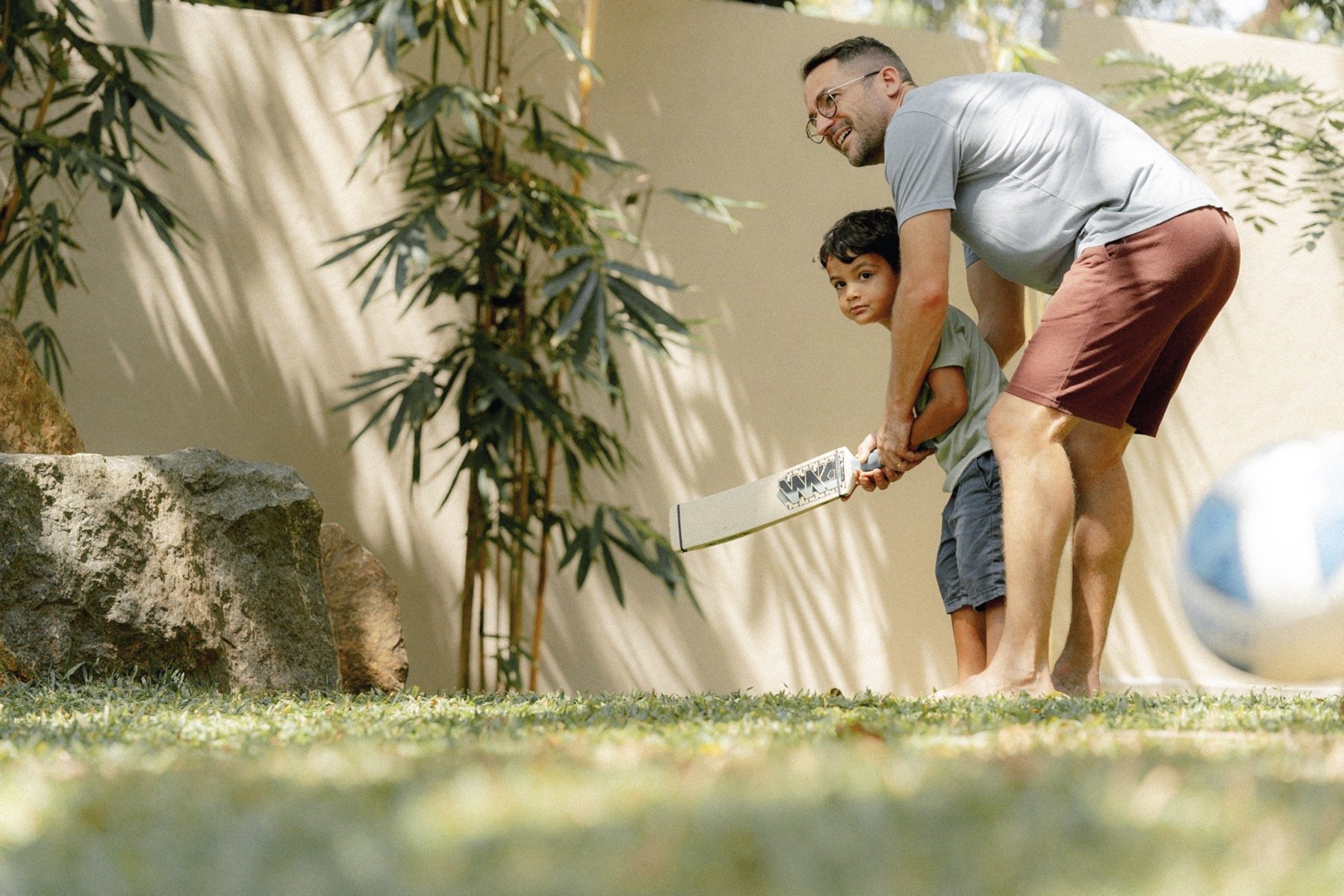 Adult and child playing cricket in a garden