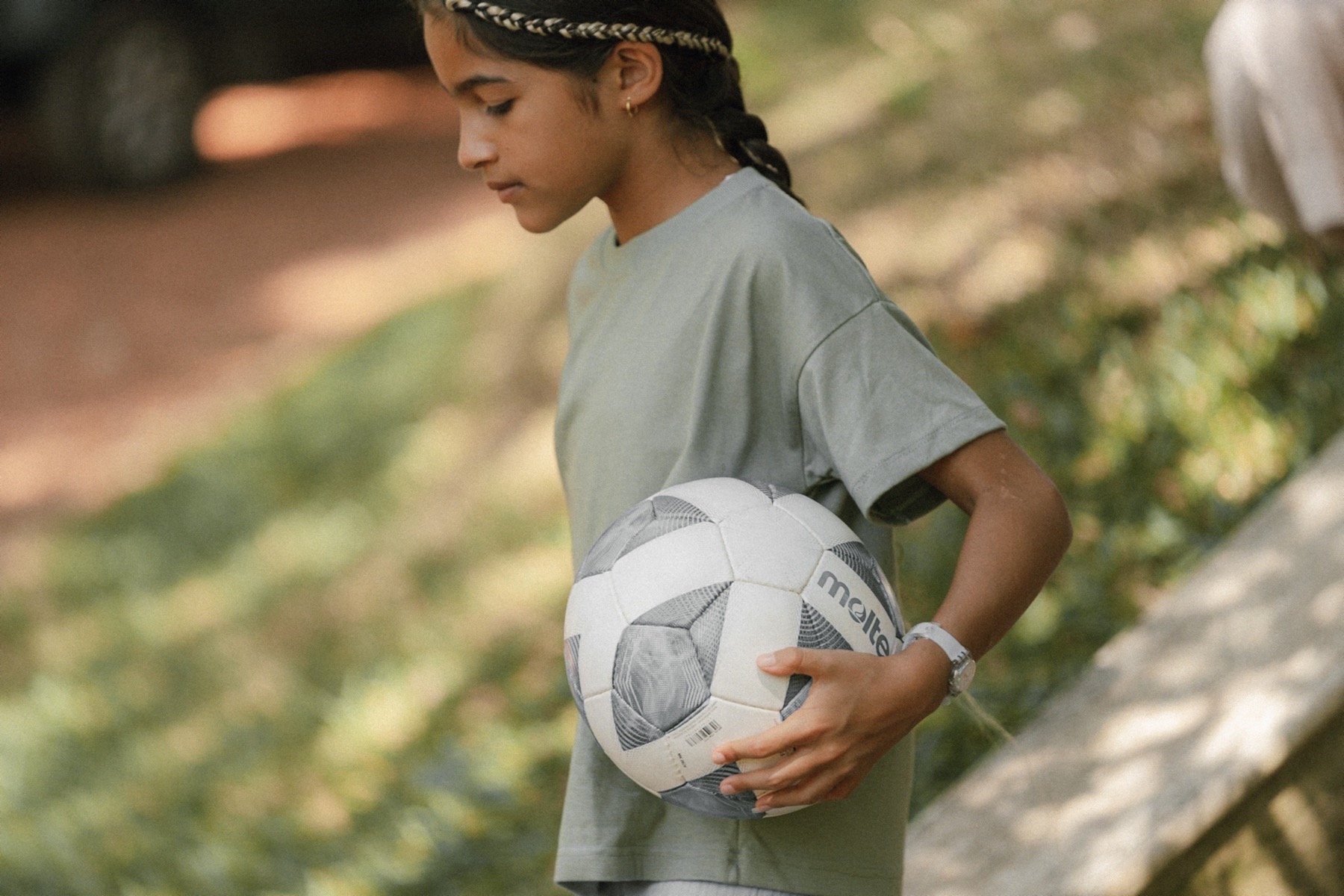 Young person holding a soccer ball outdoors.