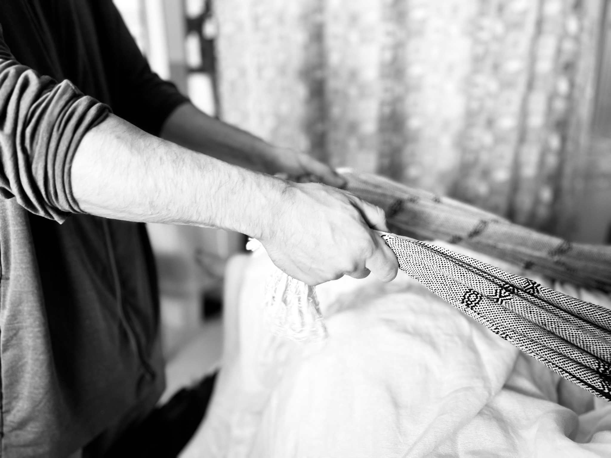 Close up of hands and arms of the partner of a laboring person is using the Rebozo scarf to help sift hips and buttocks to help align baby for optimal positioning for childbirth.