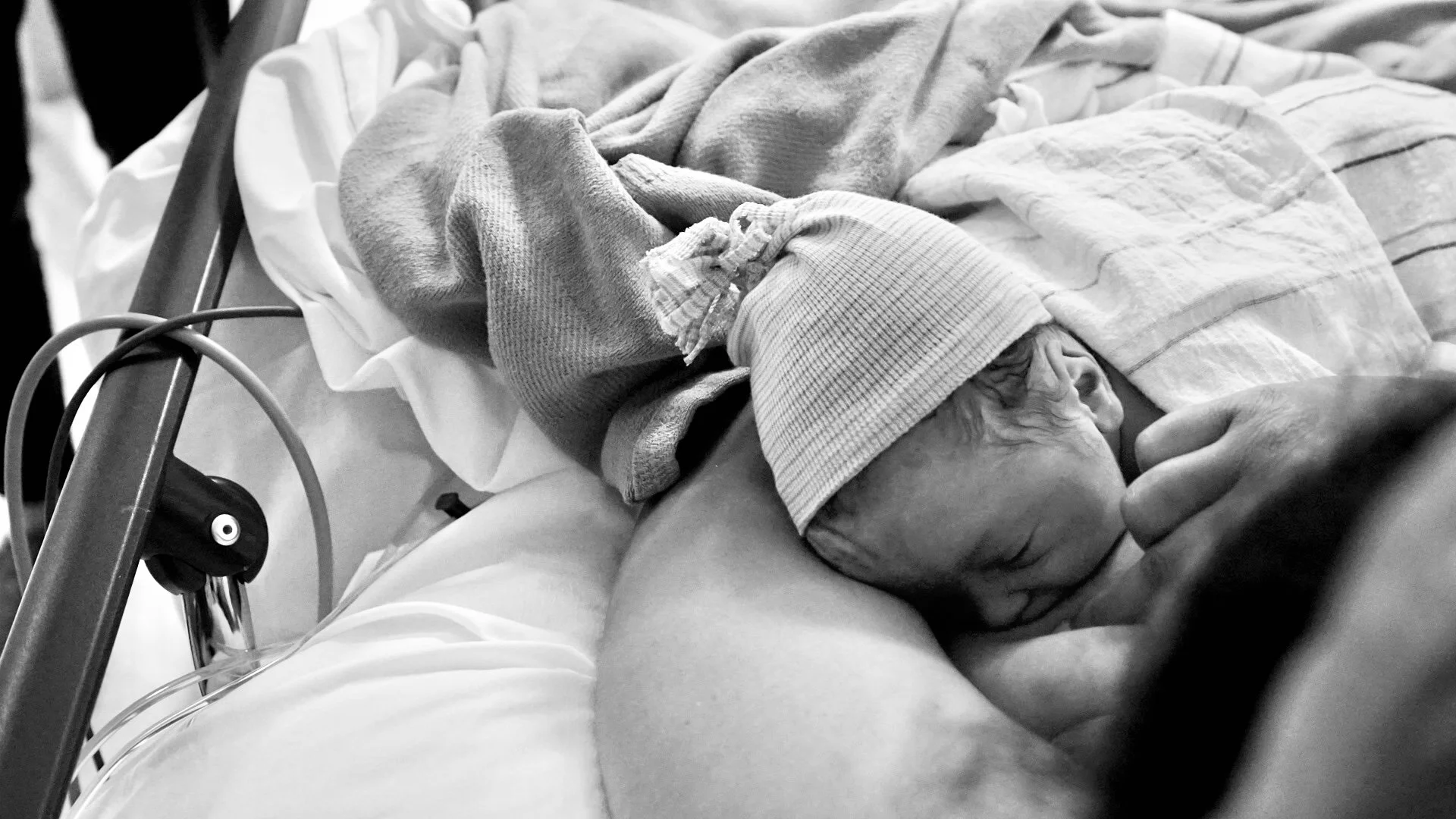 A newborn baby in mother's arms, first latch, recovery after cesarean birth.