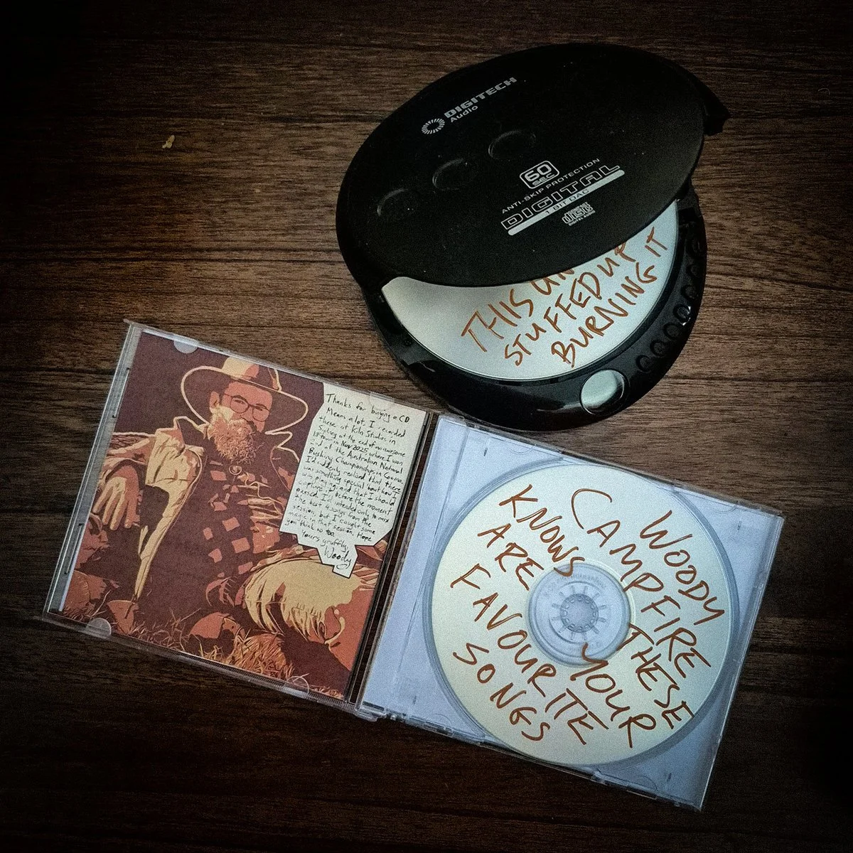 Open jewel case of "Australia's 2nd Best Busker" by Woody Campfire, with disc in CD discman.