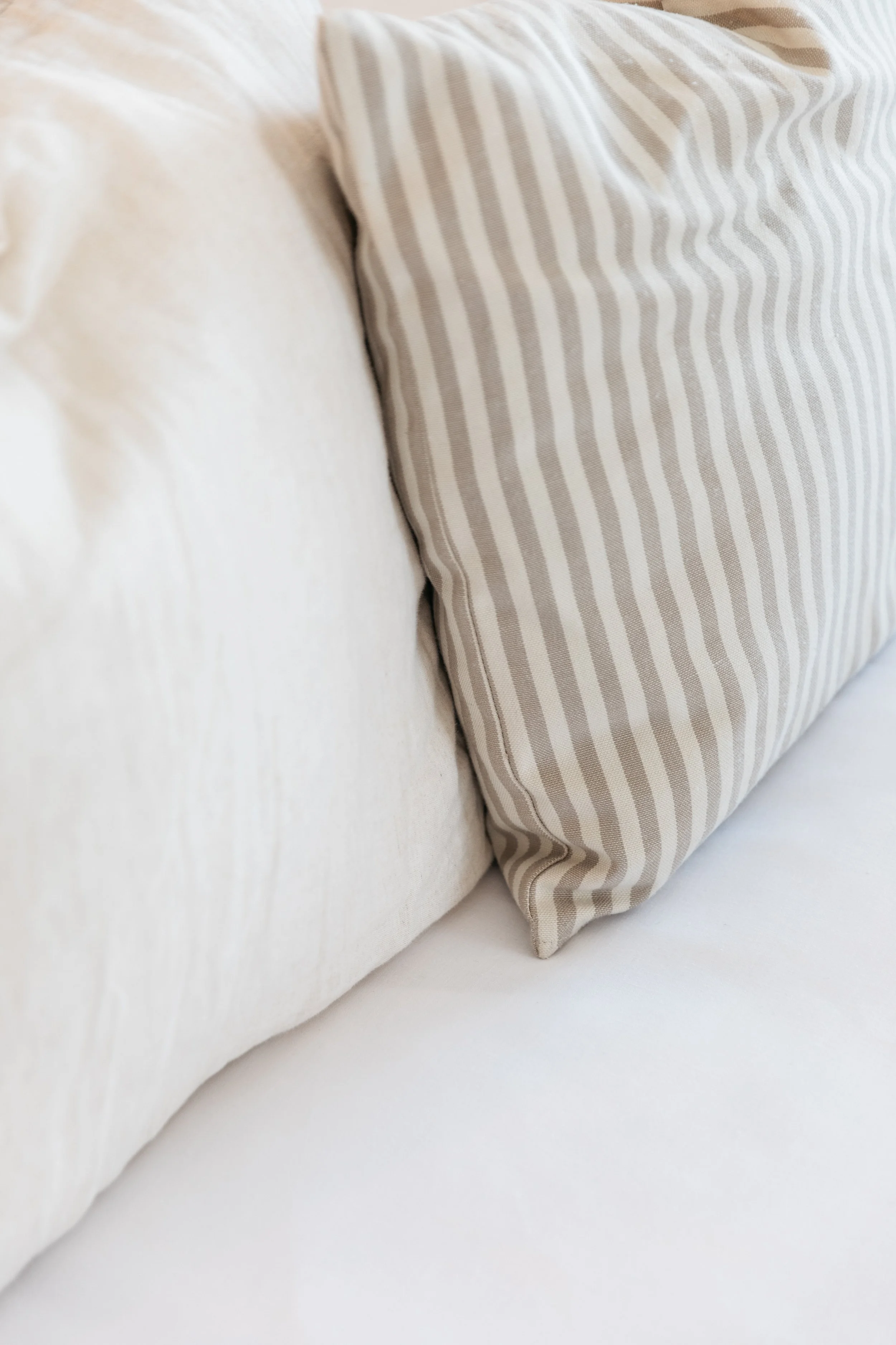 Close-up of a beige sofa with a beige striped throw pillow.