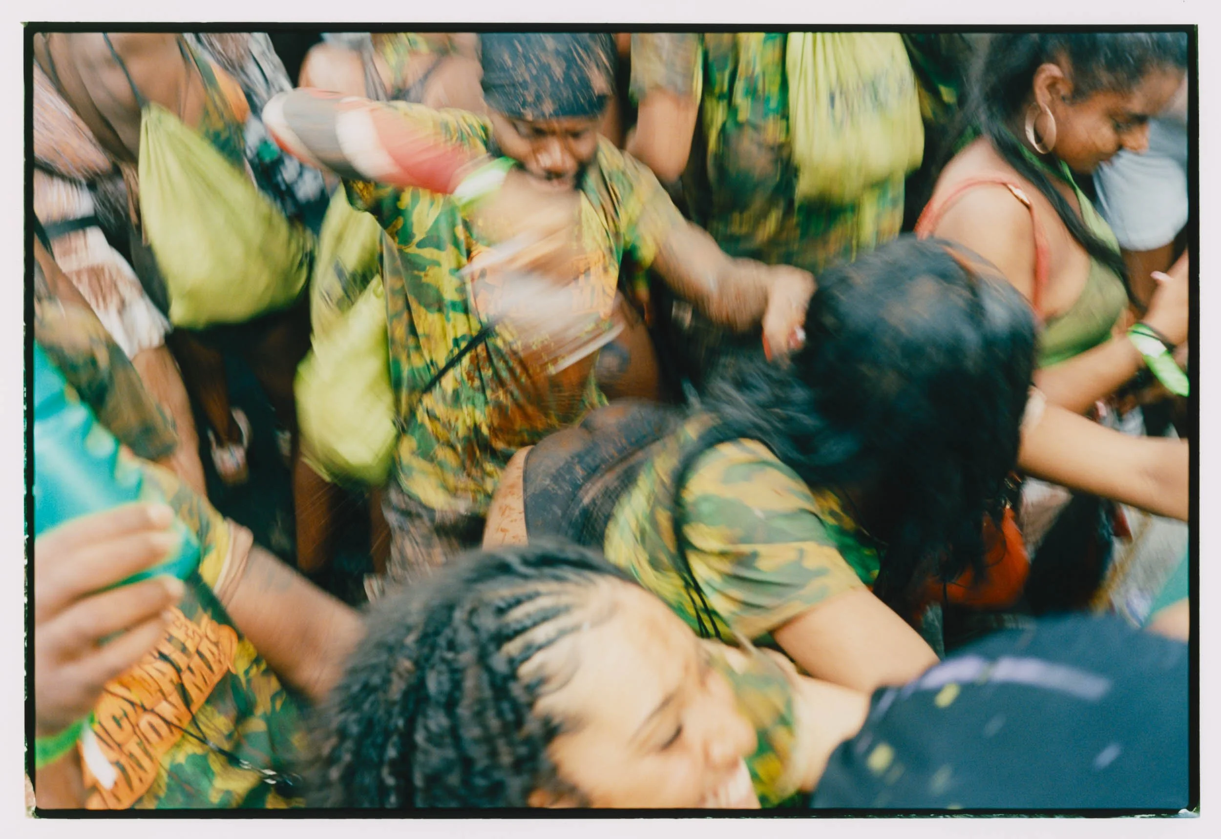 A group of people wearing colorful traditional clothing, some with mud on their faces, participating in a communal activity or celebration.