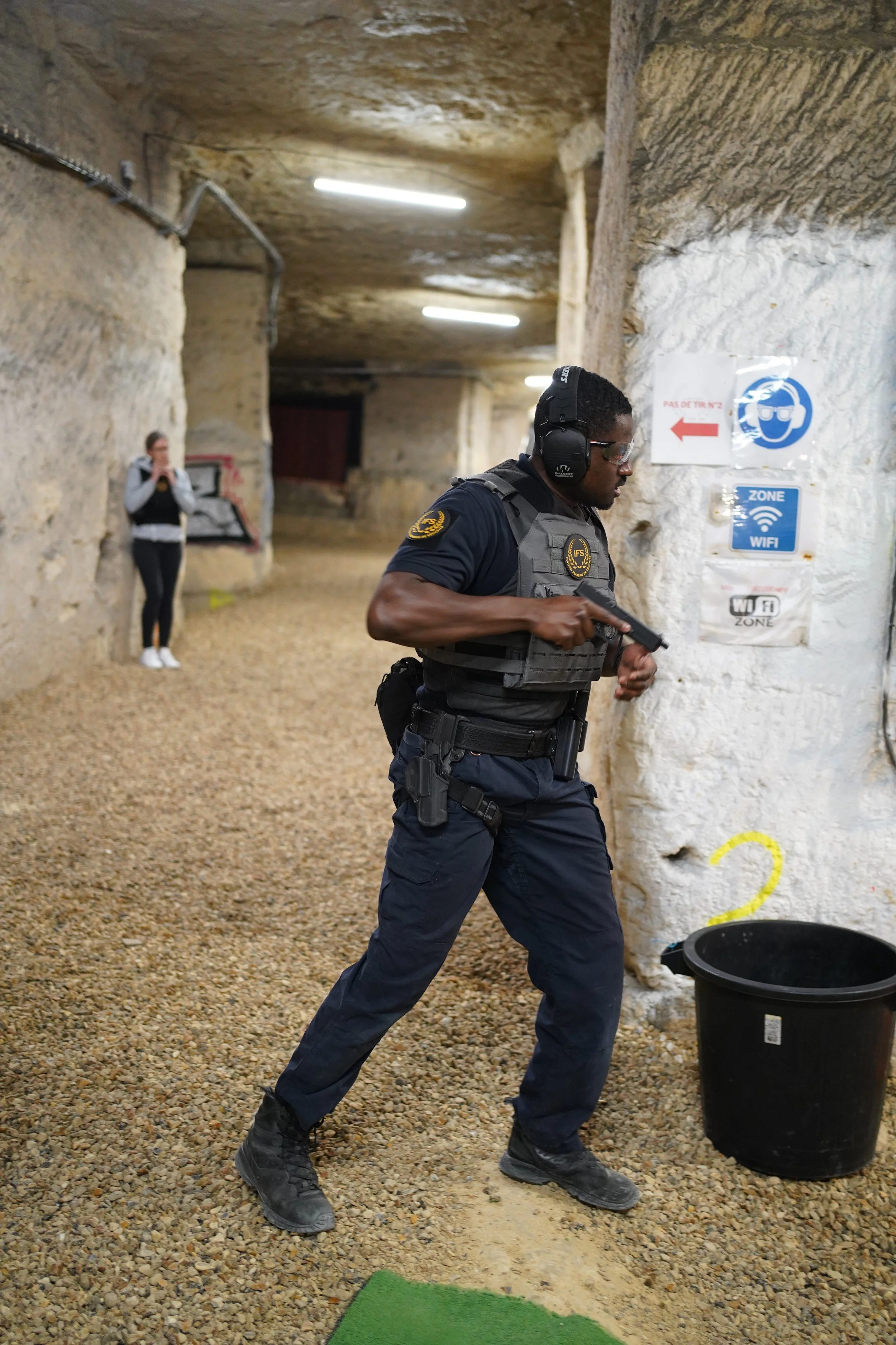 Un stagiaire en uniforme de sécurité tenant un pistolet semi automatique dans un pas de tir en sous sol