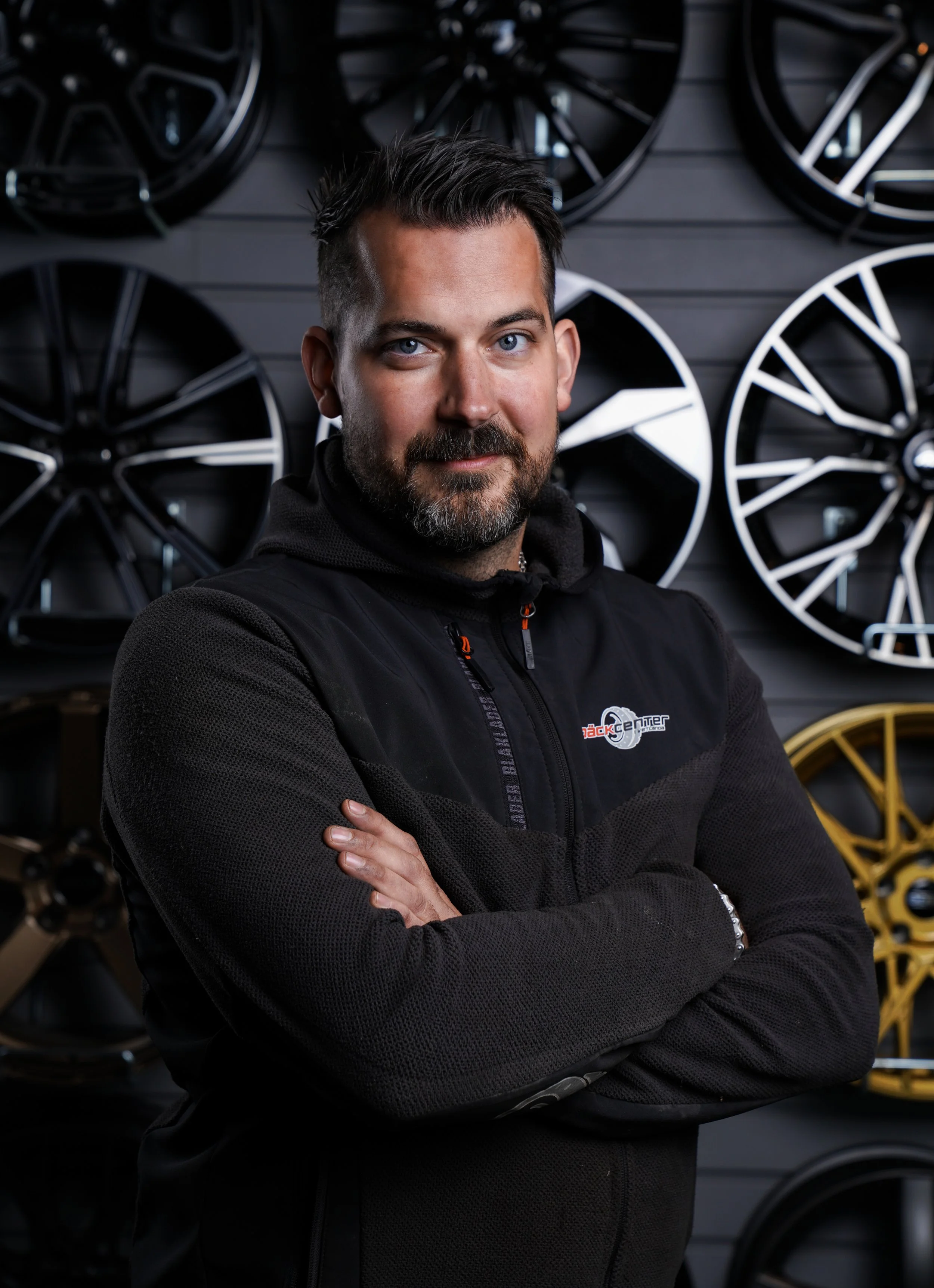 En ung kvinna med lockigt hår, glasögon, örhängen och ett leende, som tittar direkt mot kameran.