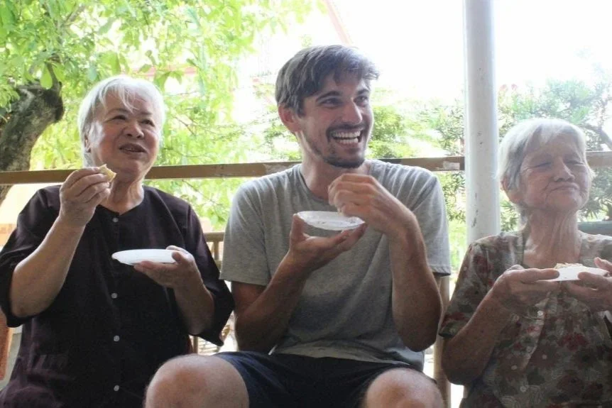 Willem met deelt een pannenkoek met twee dames in Ho chi Minh