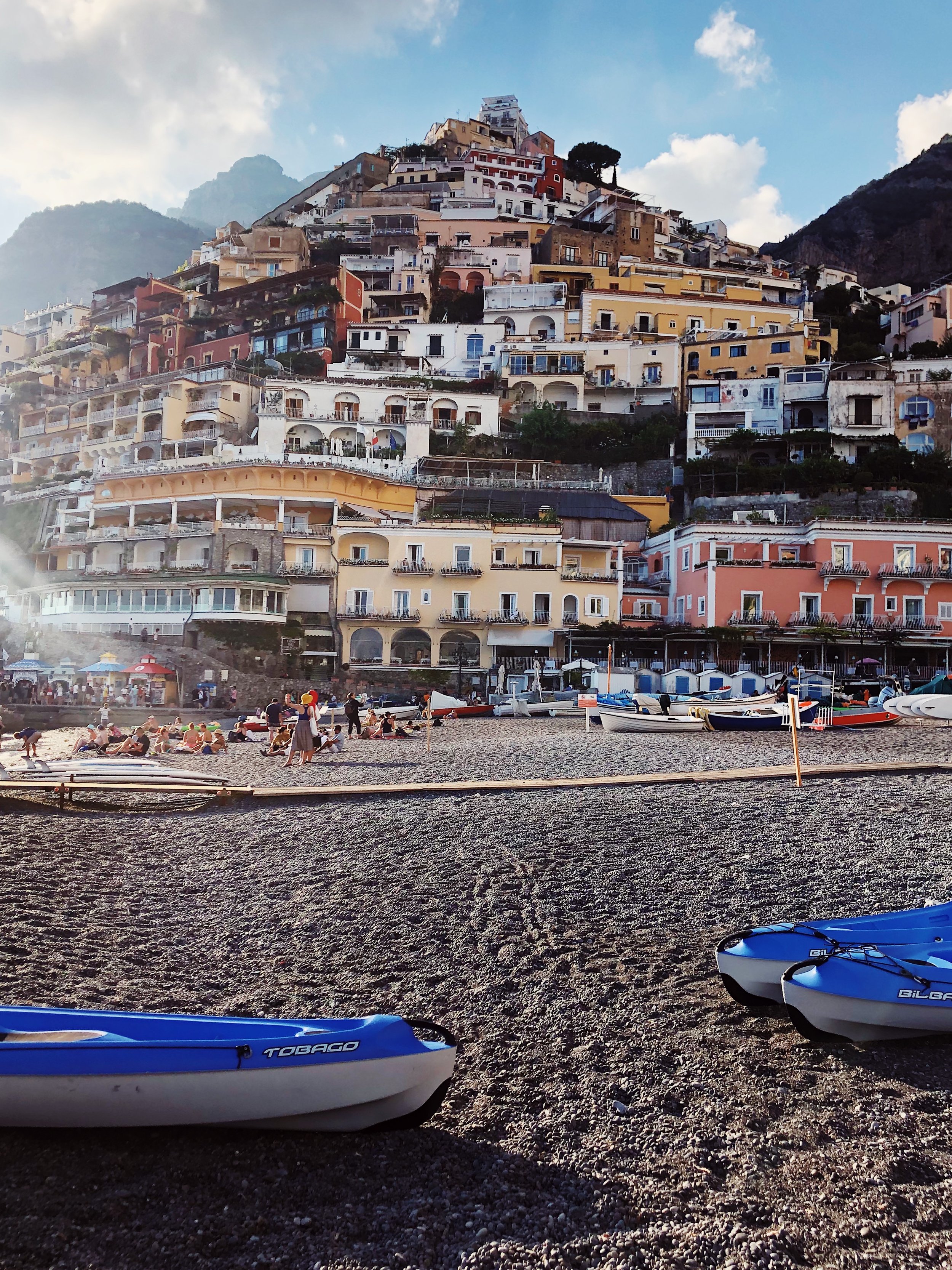 Colorful buildings on a hillside overlooking a beach with kayaks and people relaxing.