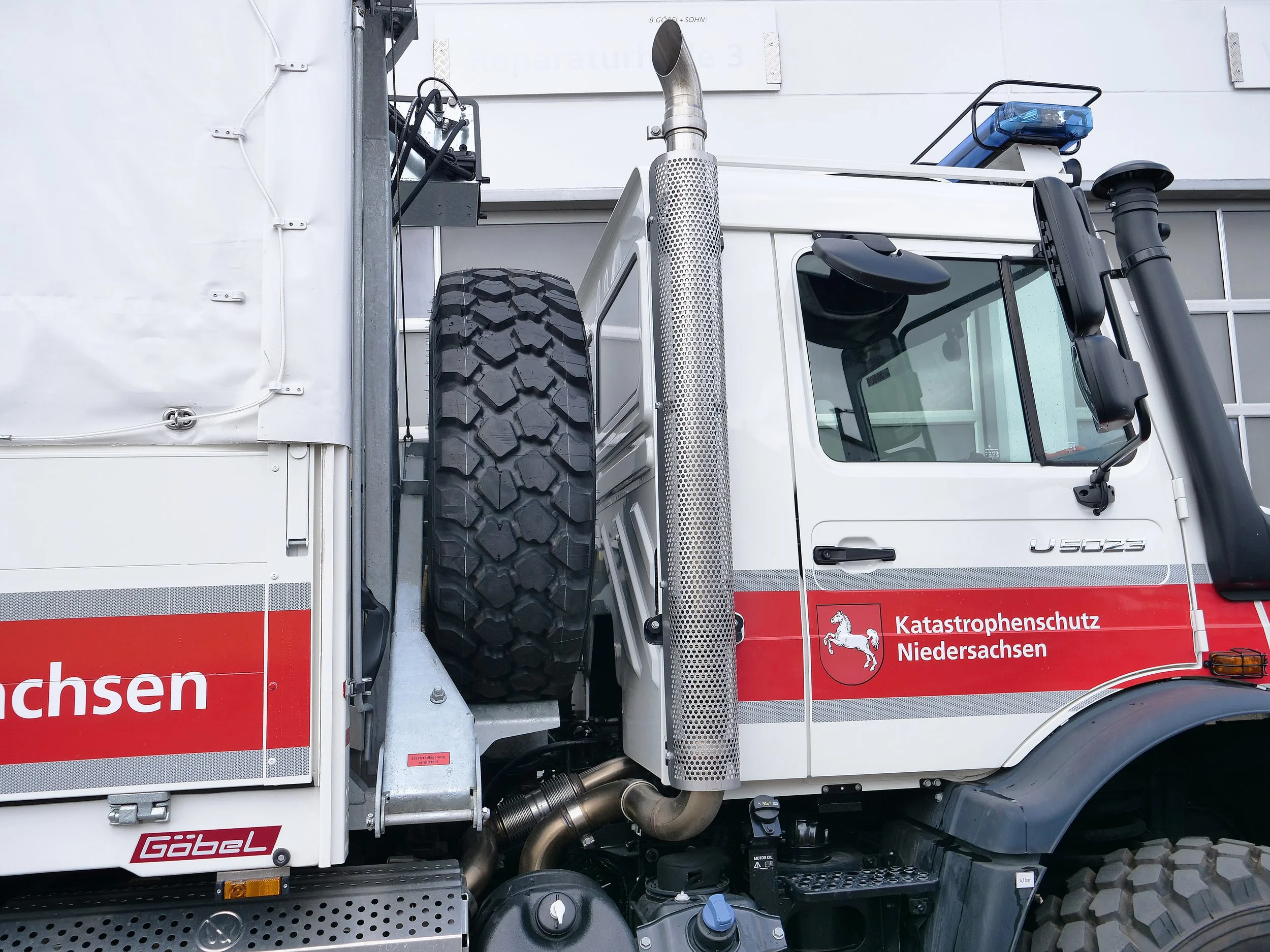 Ein Rettungswagen der Feuerwehr mit einem großen Reifen auf der Seite, einem Auspuff, einer blauen Warnlampe und dem Logo der Katastrophenschutz Niedersachsen.