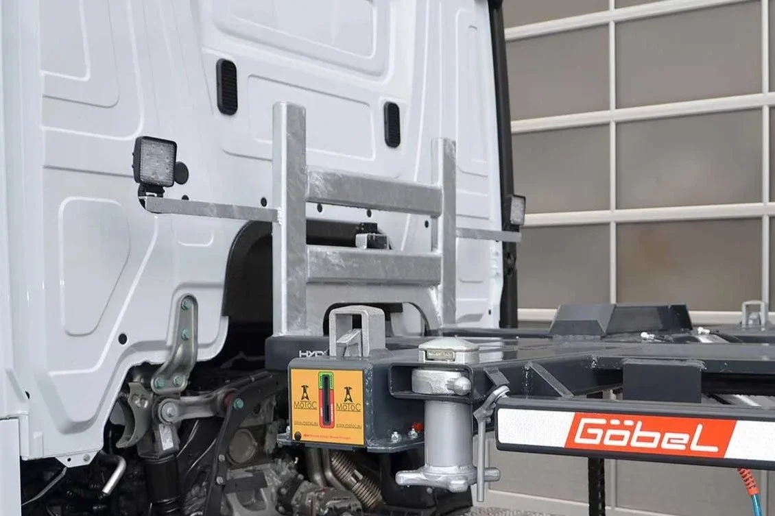Nahaufnahme des Hinterteils eines weißen Nutzfahrzeugs mit technischem Anbau, deutschem KFZ-Kennzeichen, und Add-On mit Gabelstaplerartige Anbauvorrichtung, vermutlich für den Materialtransport oder das Heben schwerer Gegenstände.