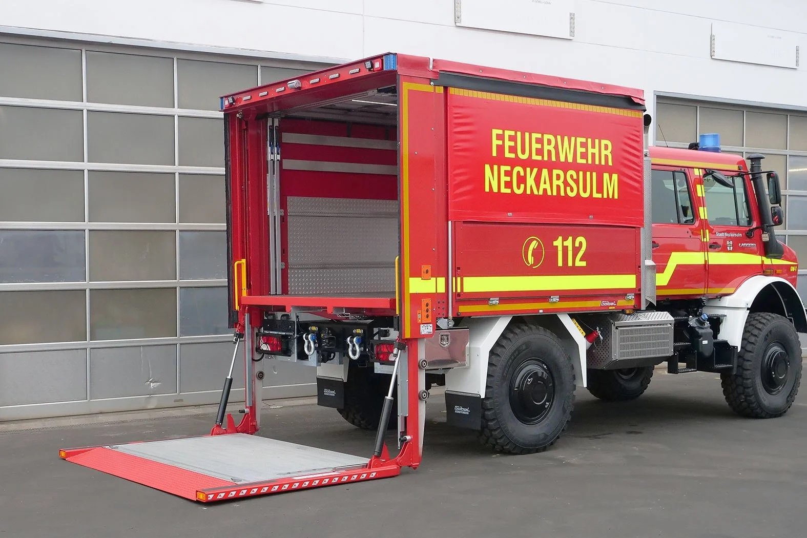 Gerätewagen Logistik Mercedes Benz Unimog für Feuerwehr Neckarsulm aufgebaut von Göbel Fahrzeugbau, seitliche Heckansicht mit runtergelassener Ladebordwand