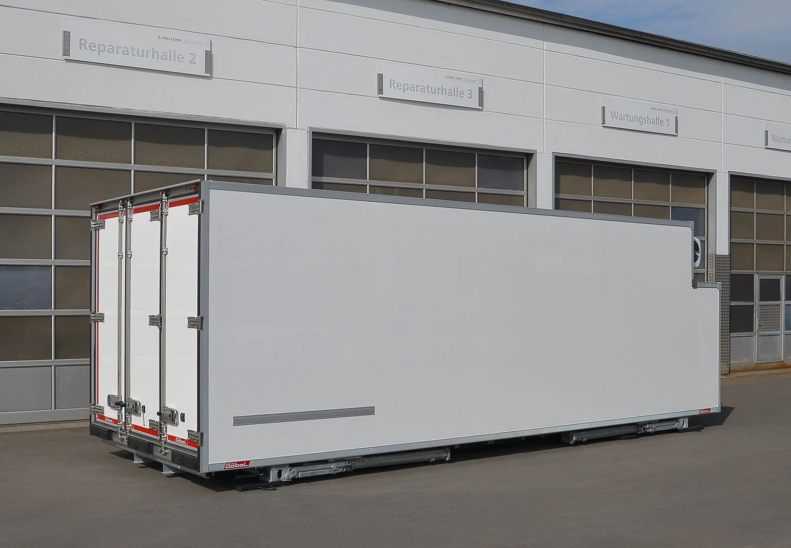 Ein leerer, weißer Transporter vor einer Werkstatt mit Beschilderung in Deutsch.
