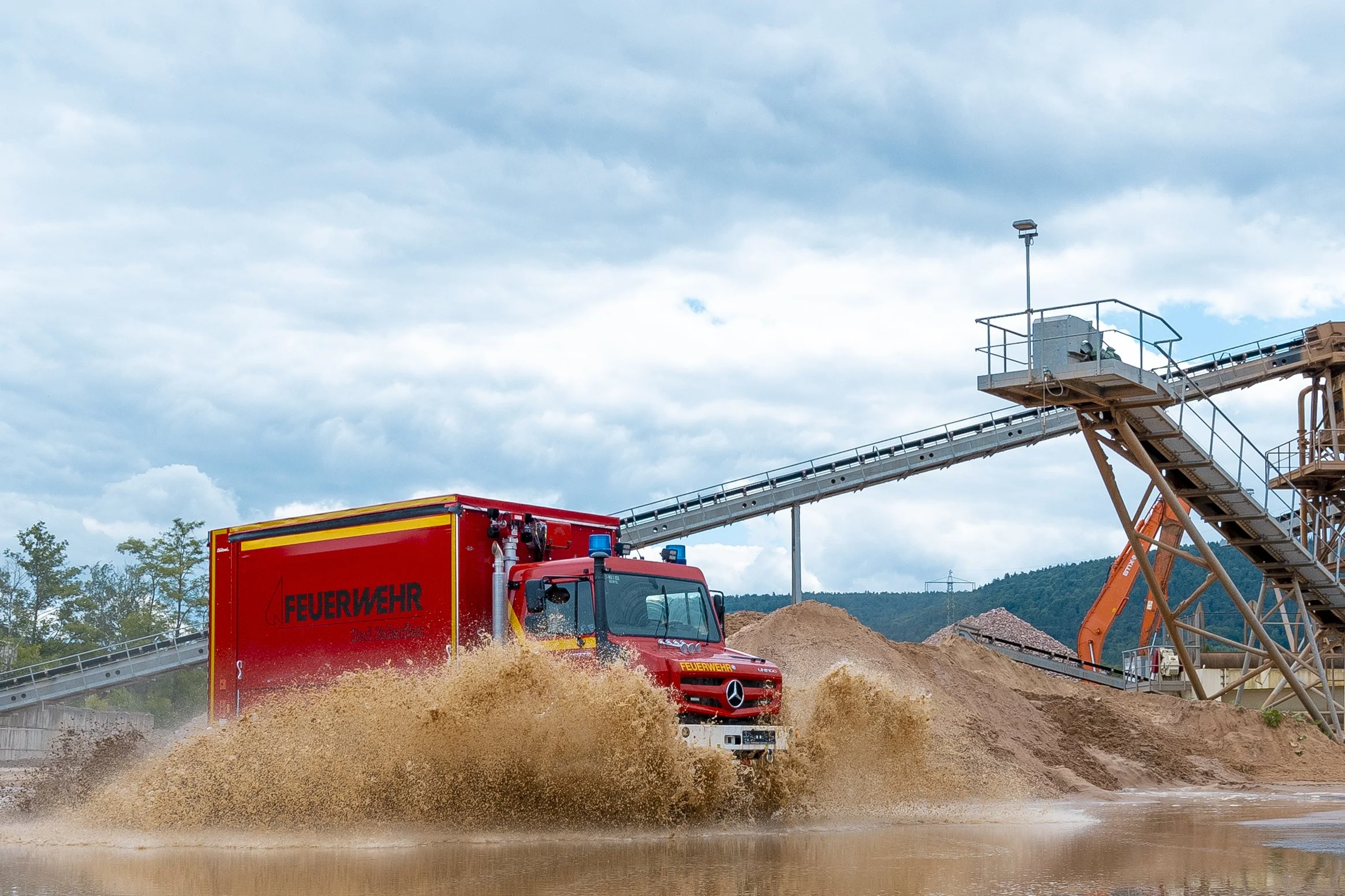 Mercedes Benz Einsatzfahrzeug der Feuerwehr Bad Salzufen aufgebaut von Göbel Fahrzeugbau fährt durch Pfütze