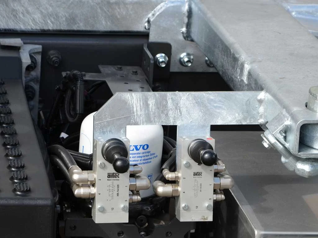 Maschine mit Edelstahlkomponenten, einem weißen Filter und schwarzen Kabeln, vermutlich Teil eines technischen oder mechanischen Systems.