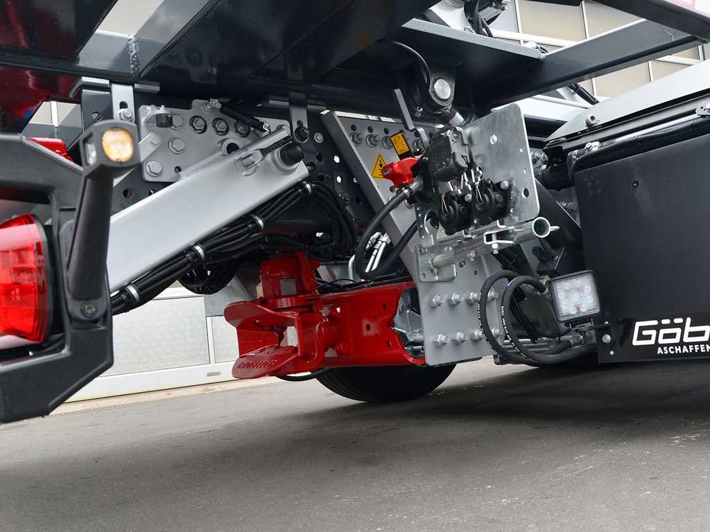 Nahaufnahme des Unterbodens eines Fahrzeugs, zeigt hydraulische Komponenten, Kabel und Metallteile.