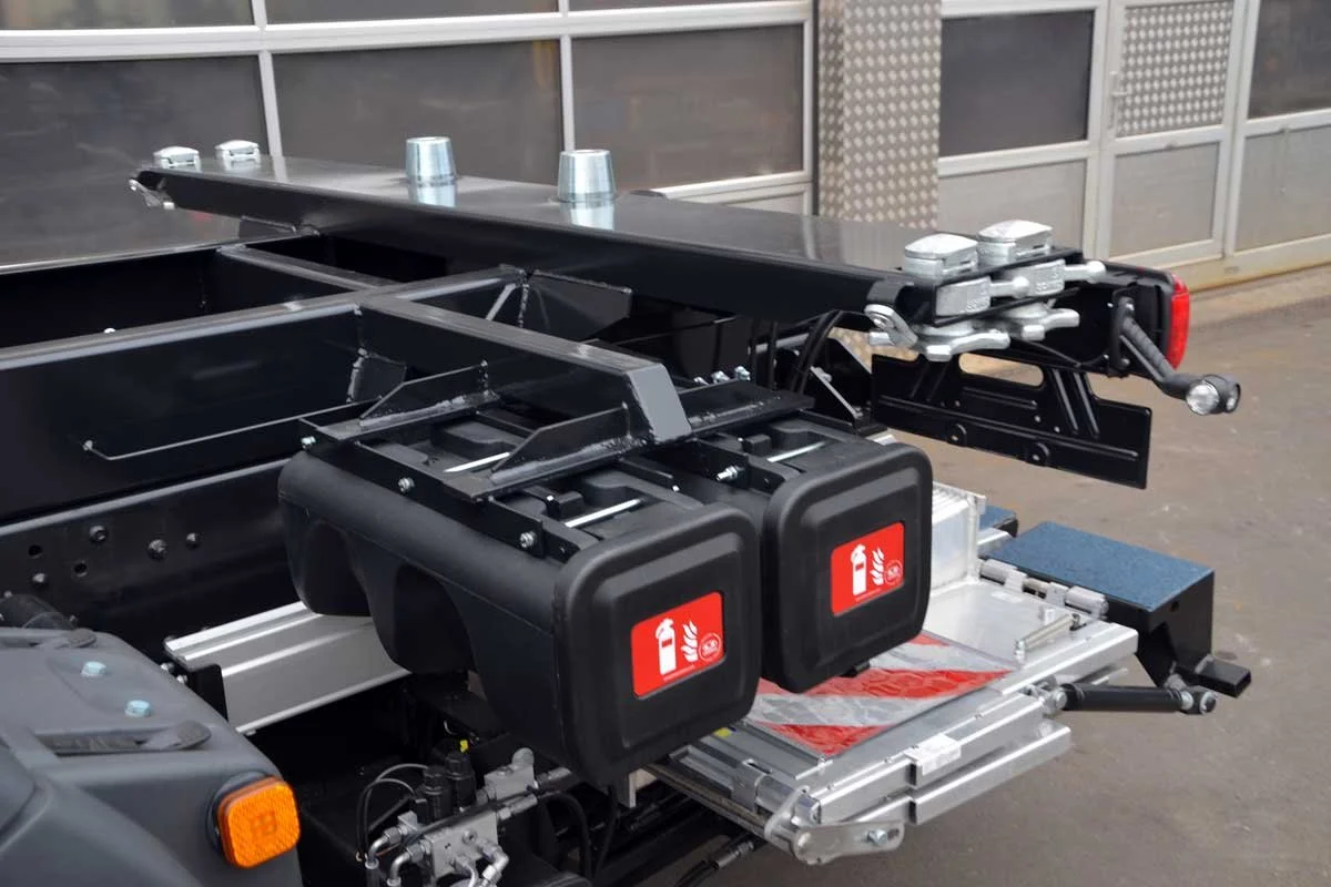 Nahaufnahme einer elektrischen Fahrzeugplattform mit Feuerlöschern und verschiedenen technischen Komponenten, wahrscheinlich für ein Feuerwehrfahrzeug.