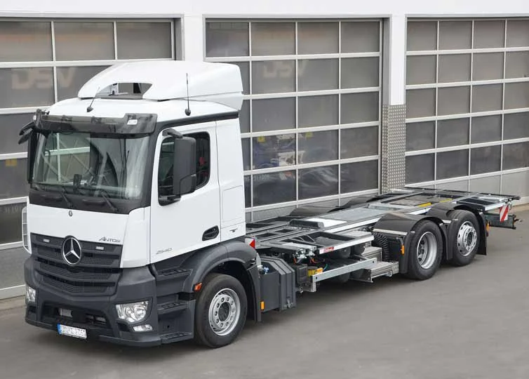 Ein weißer Mercedes-Benz Lkw ohne Auflieger vor einer modernen Garage