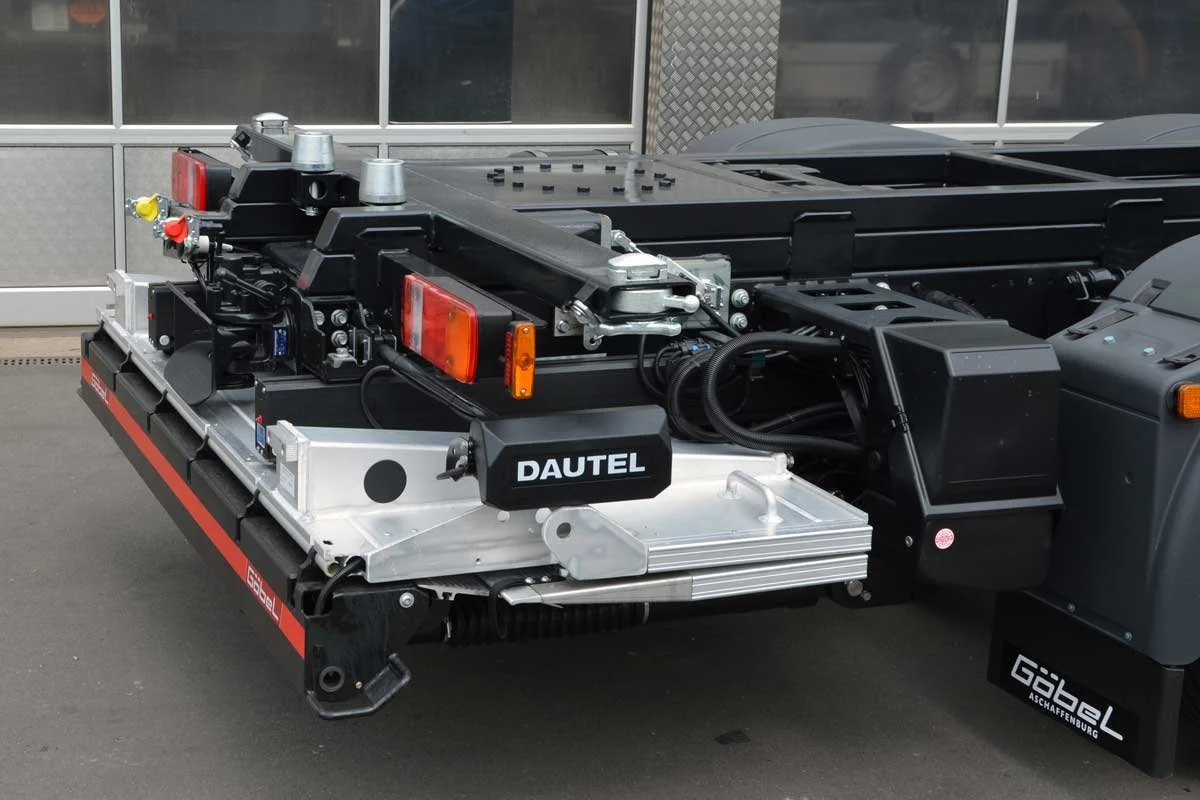 Nahaufnahme eines Lkw-Anhängers mit technischem Equipment, darunter Hydraulikzylinder, Kabel, Reflektoren und die Markierung "DAUTEL" auf einer schwarzen Box.