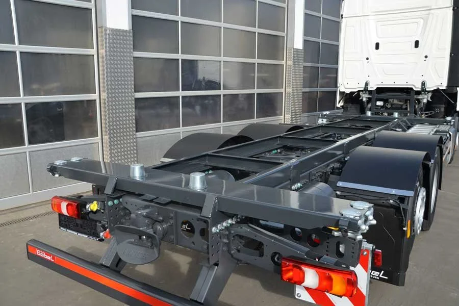 Leerer LKW-Chassis vor einer Lagerhalle.