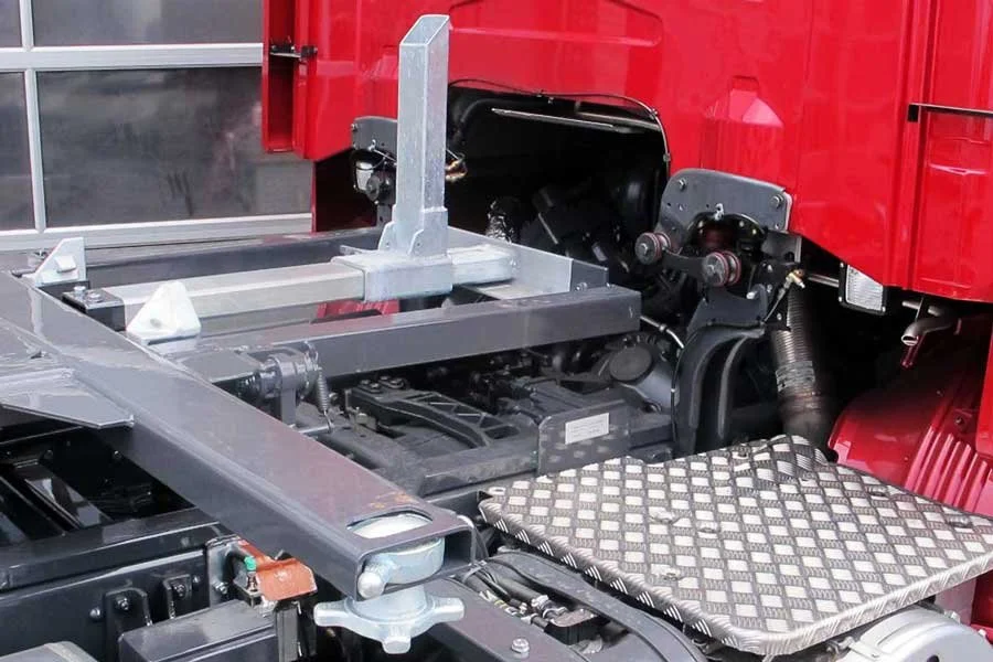 Nahaufnahme des Motorraums eines roten Fahrzeugs, zeigt mechanische Komponenten, Rahmen und Sitzelemente.
