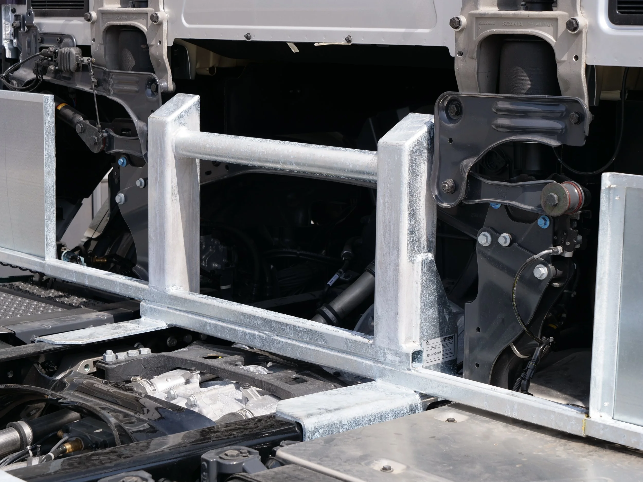 Nahaufnahme von mechanischen und elektrischen Komponenten in einem technischen Gerät, vermutlich an einem Fahrzeug oder einer Maschine, mit Metallrahmen und Schrauben.