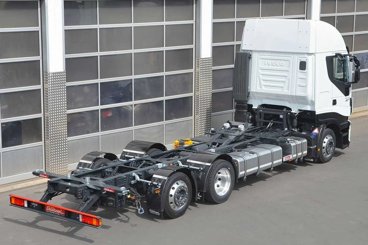 Ein weißer Iveco Lkw ohne Auflieger, bereit für den Transport, vor einer industriellen Lagerhalle.
