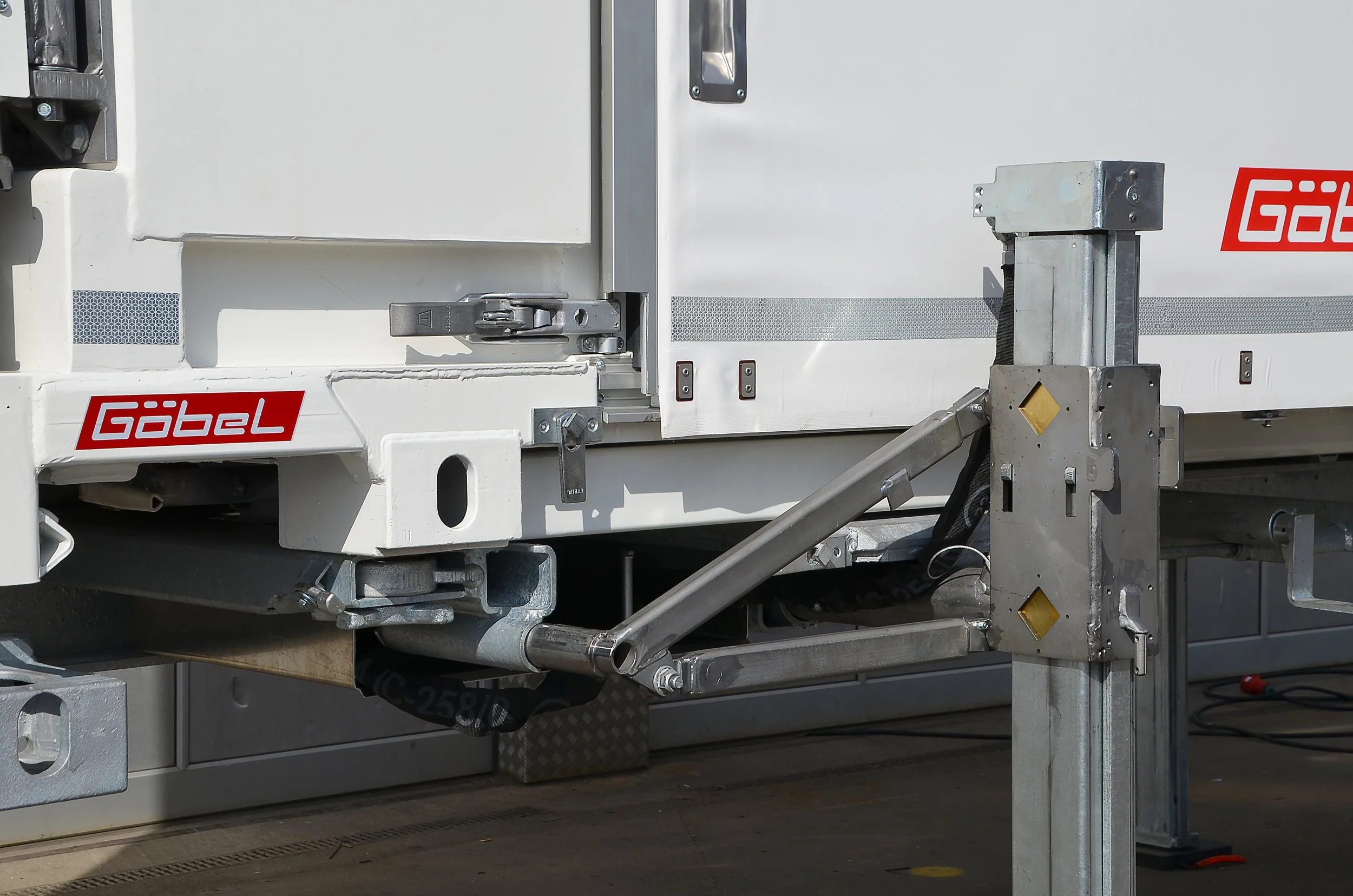 Nahaufnahme einer weißen Industriekühlfachtür mit Metallverschlussmechanismus und Beschlägen, auf einem LKW, mit einem Gabelstapler ausgestattet.