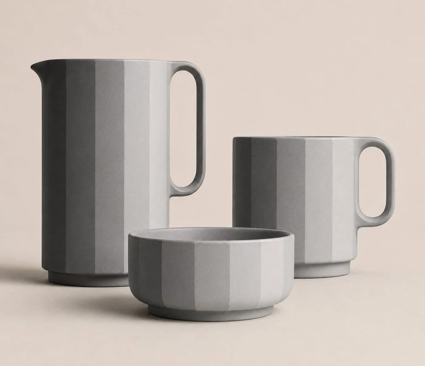 Set of three gray striped ceramic cups and a pitcher on a beige background.