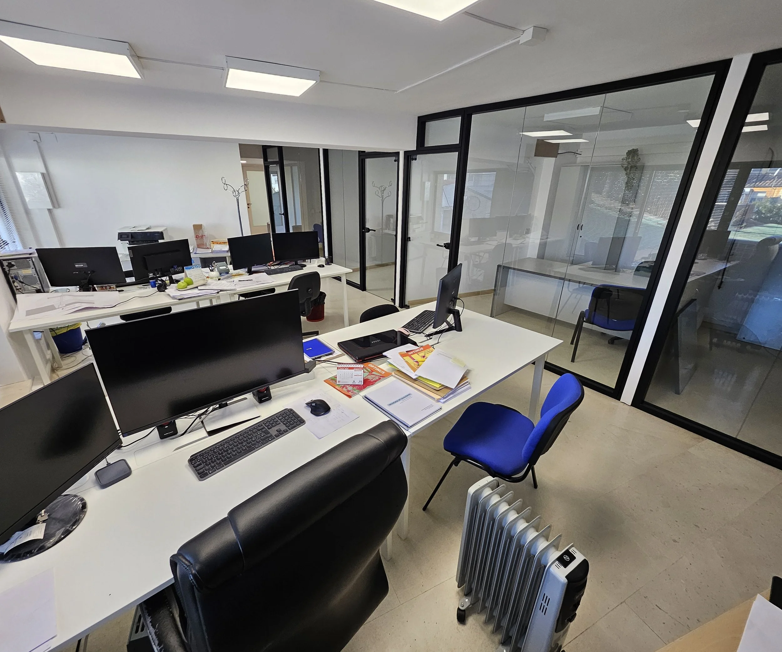 Zona de coworking con puestos de trabajo fijos y despachos acristalados en Nexum, Sant Celoni