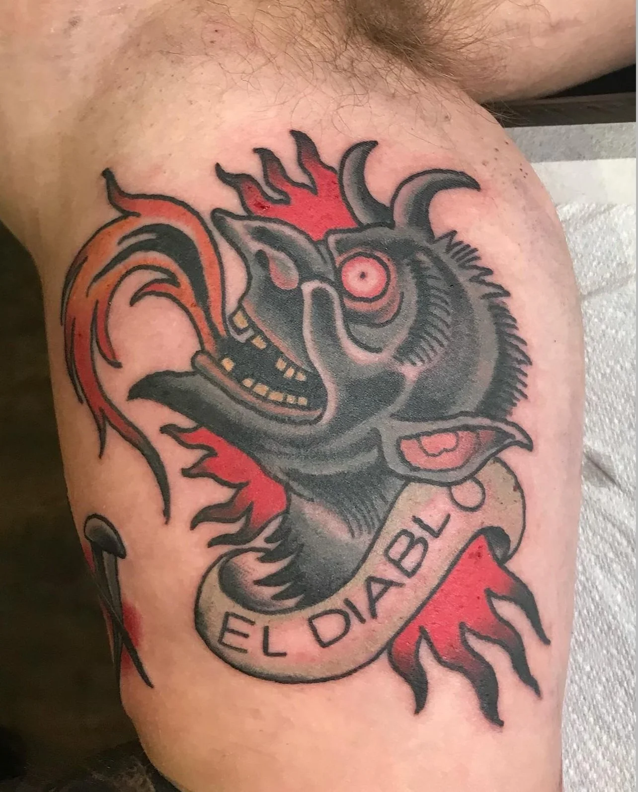 Tattoo of a demonic goat with flames and the text "El Diablo" on a person's arm.