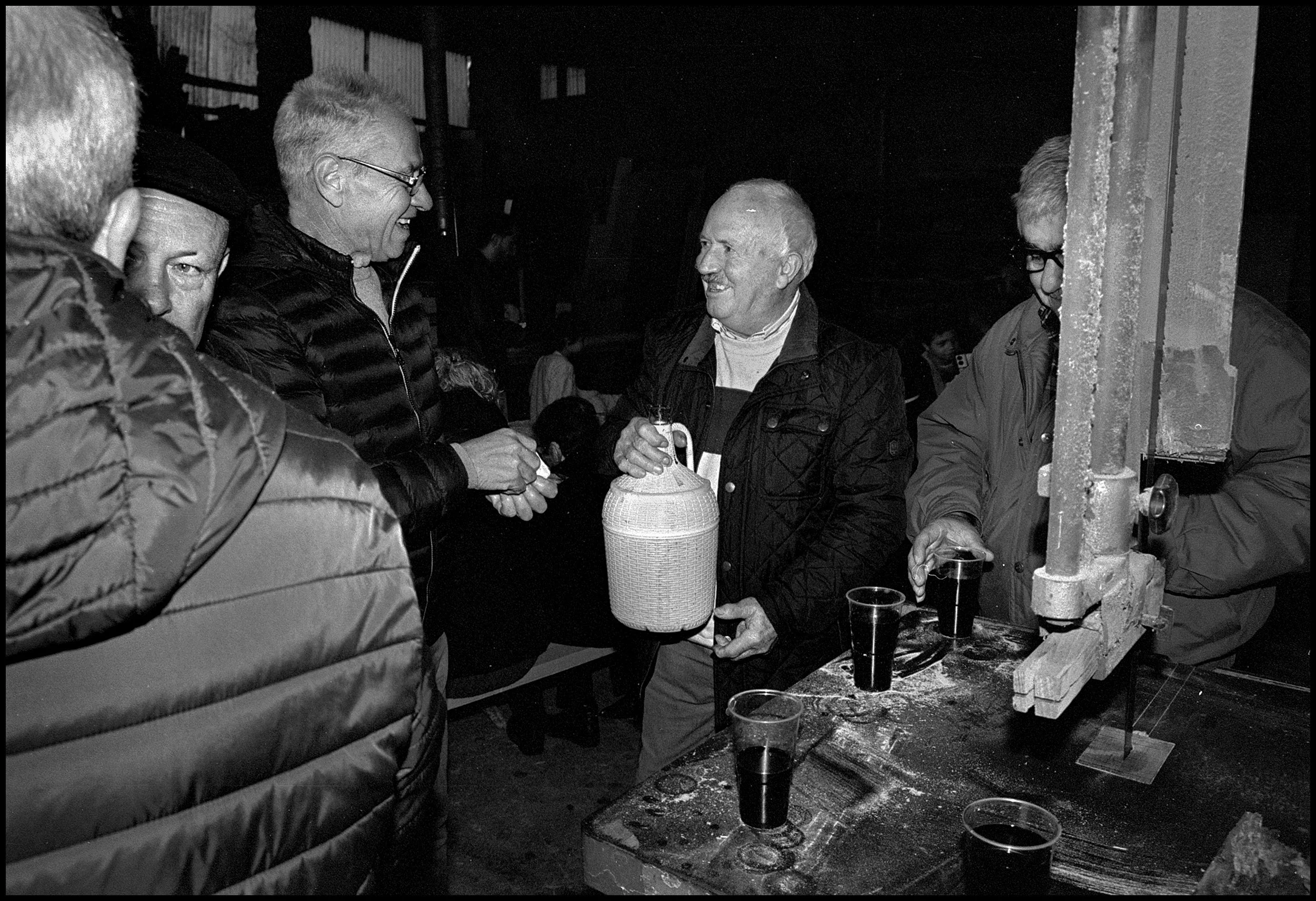 Men socializing during the village magusto. Parada do Monte, Portugal. 2025.