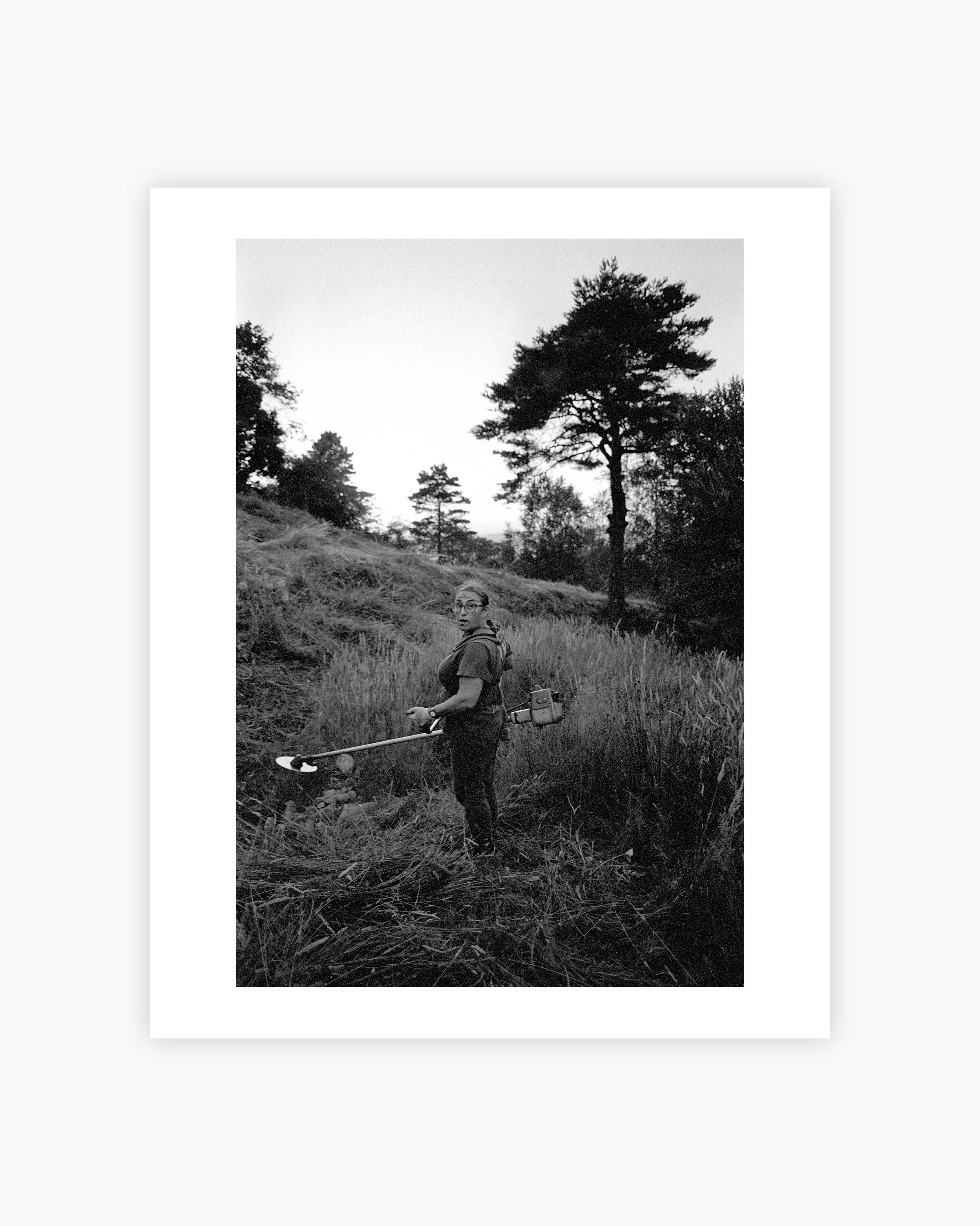 A woman in the countryside, carrying a brushcutter on her back, cutting hay. Viana do Castelo, Portugal. 2025