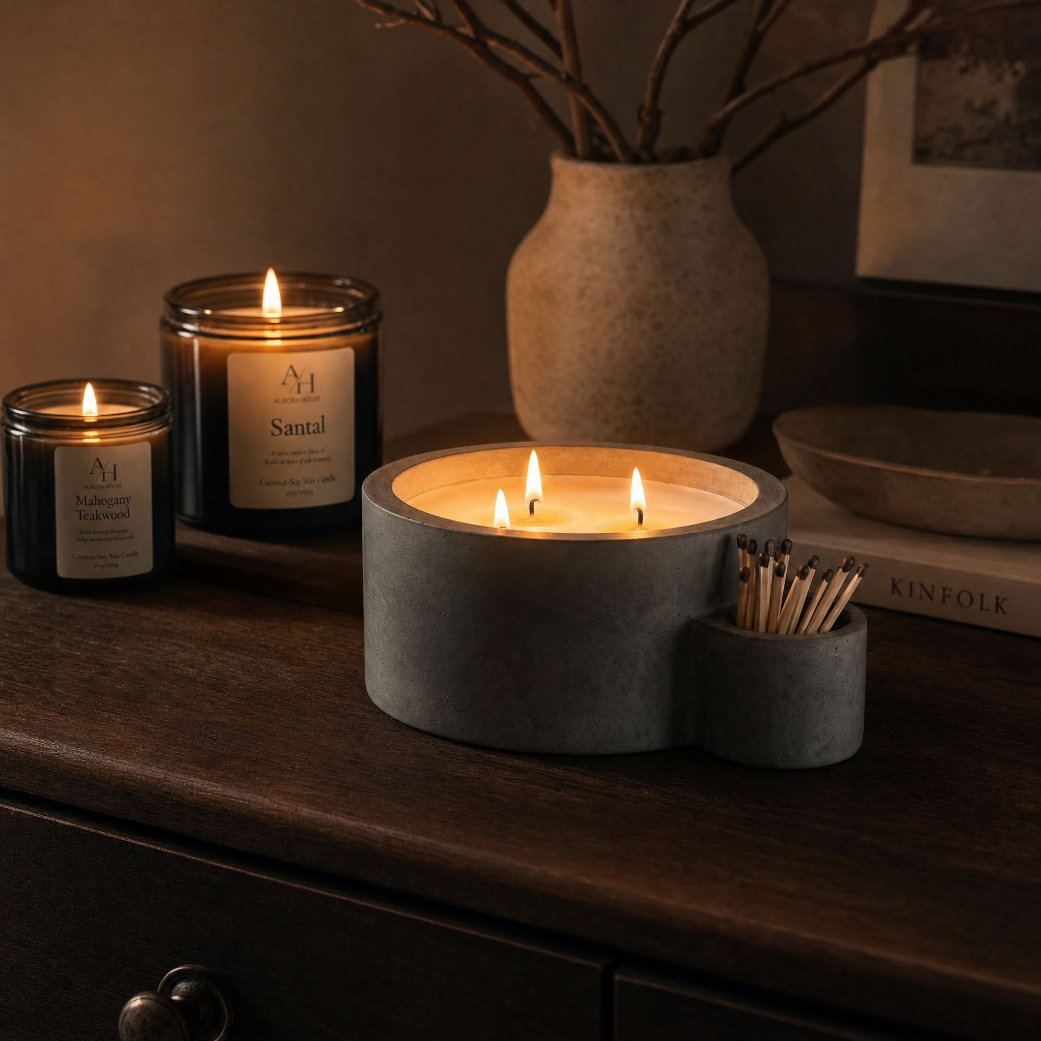 Sculptural concrete candle vessel with integrated match holder styled in a dark moody modern interior.