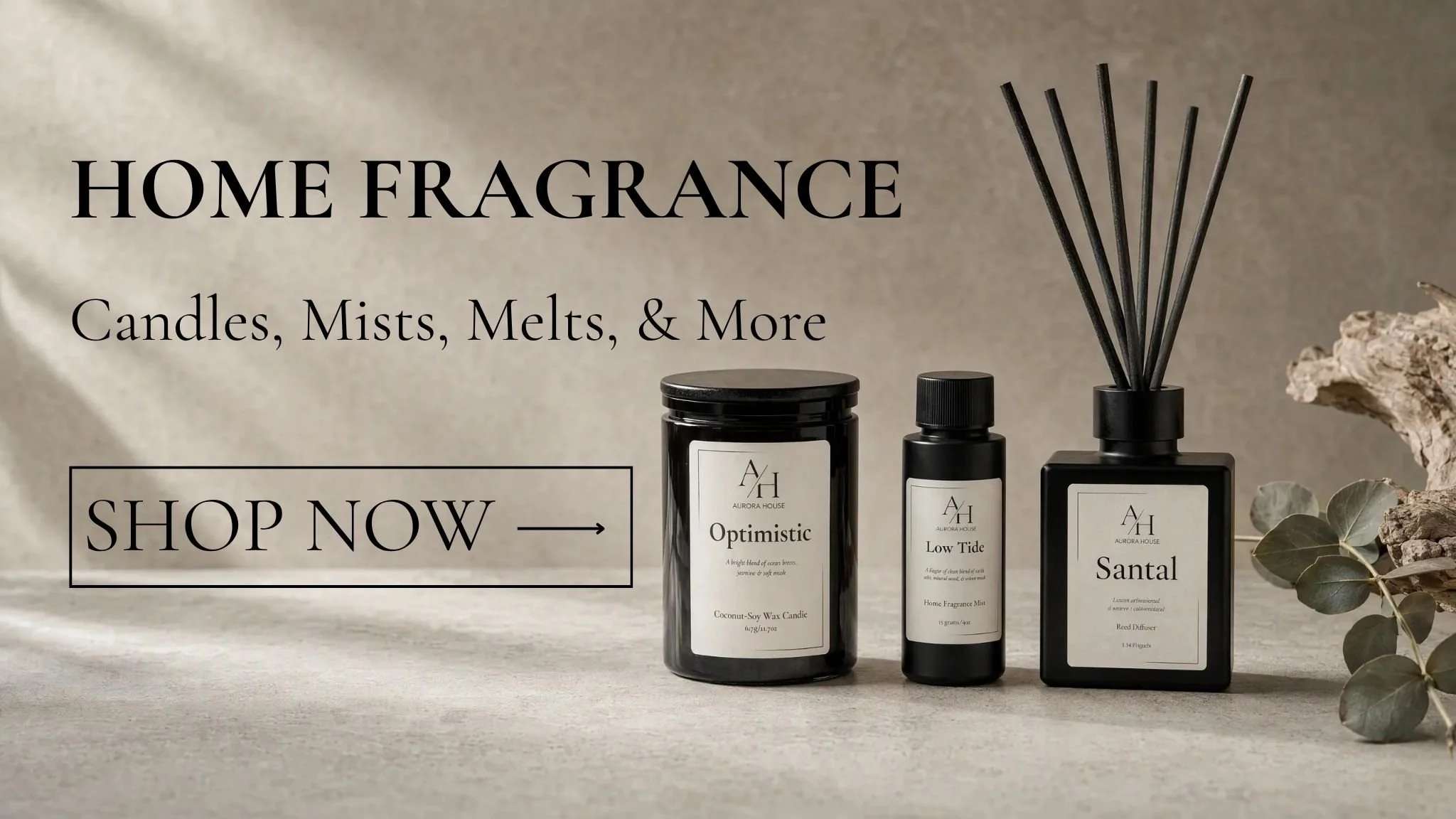 Aurora House home fragrance collection featuring an Optimistic coconut-soy candle, Low Tide home fragrance mist, and Santal reed diffuser arranged on a neutral stone surface.