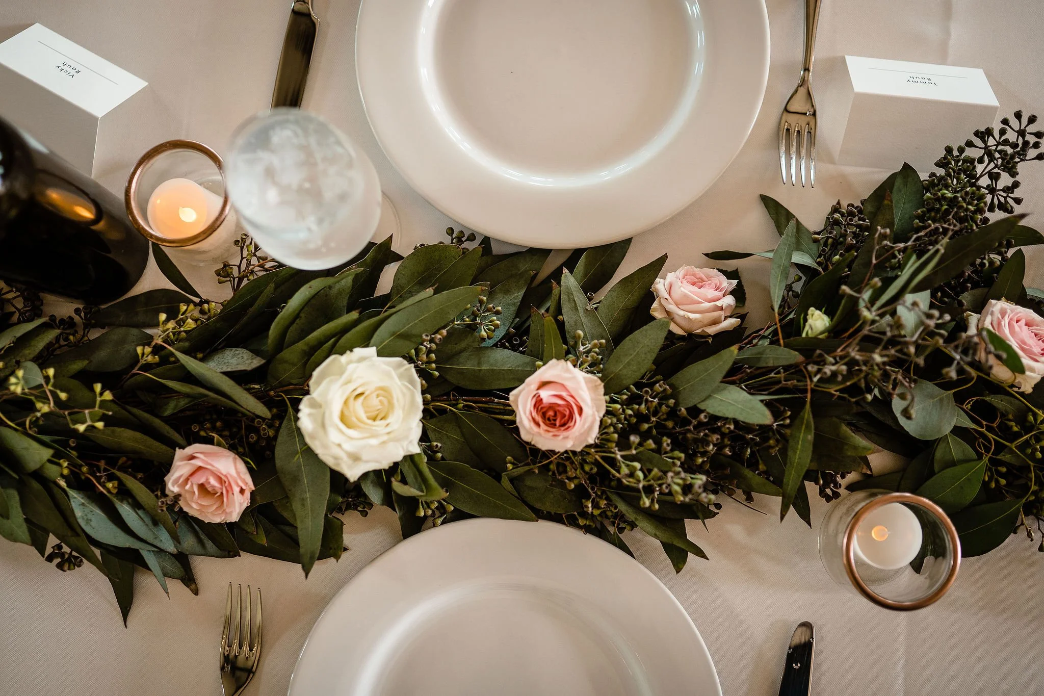 Greenery runner with pink and cream florals with white plates 